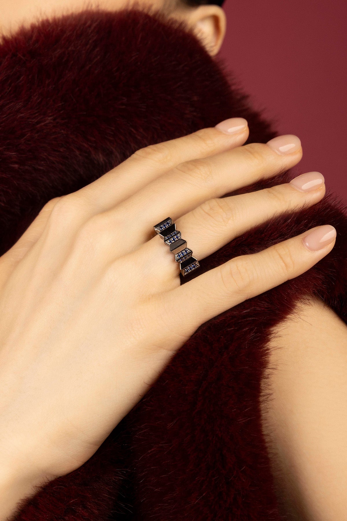 Woman wearing APM ring, une allure graphique et audacieuse sur fourrure bordeaux.