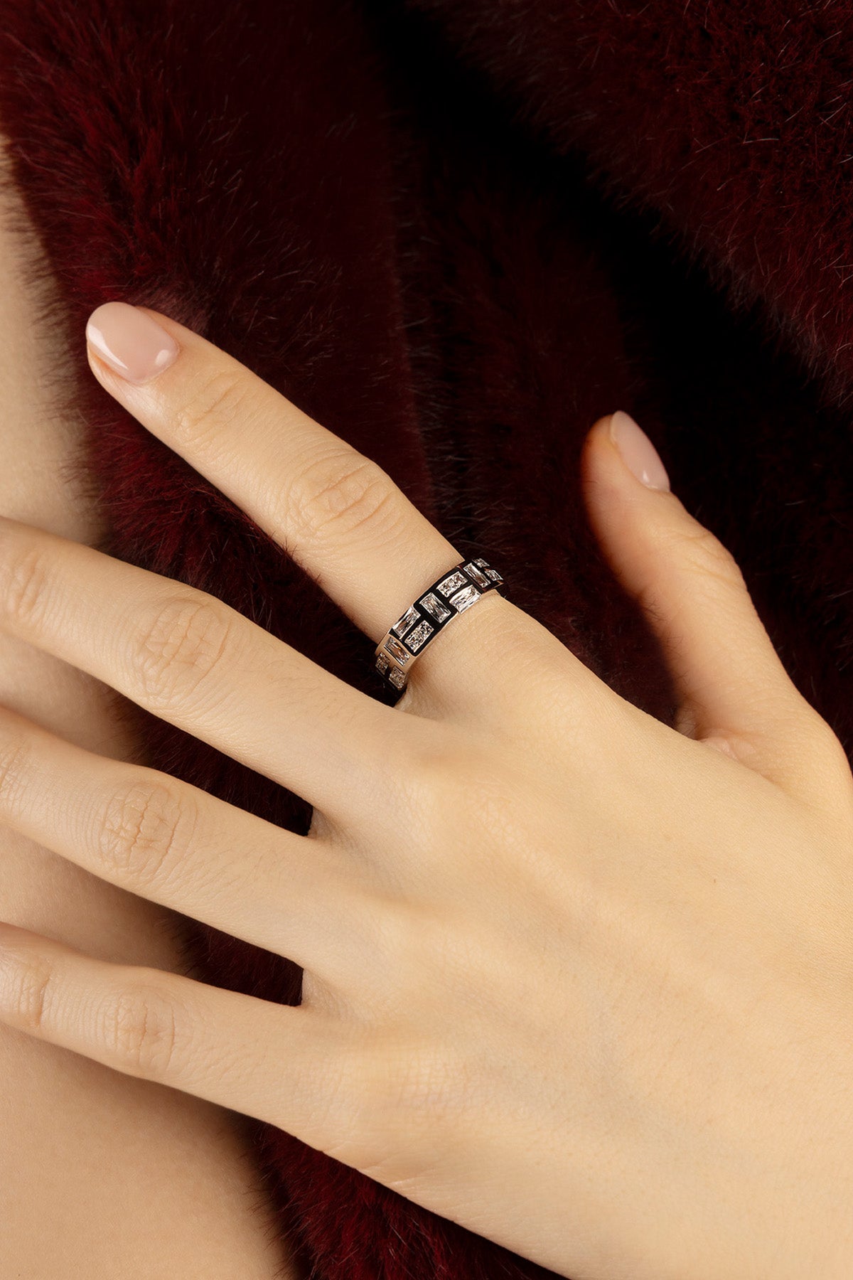 Femme portant la Bague APM, éclat graphique sur fourrure bordeaux.
