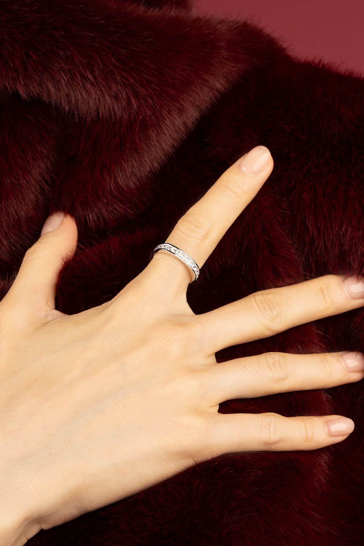 Femme portant la Bague APM Monaco, une lueur délicate posée sur la fourrure bordeaux.