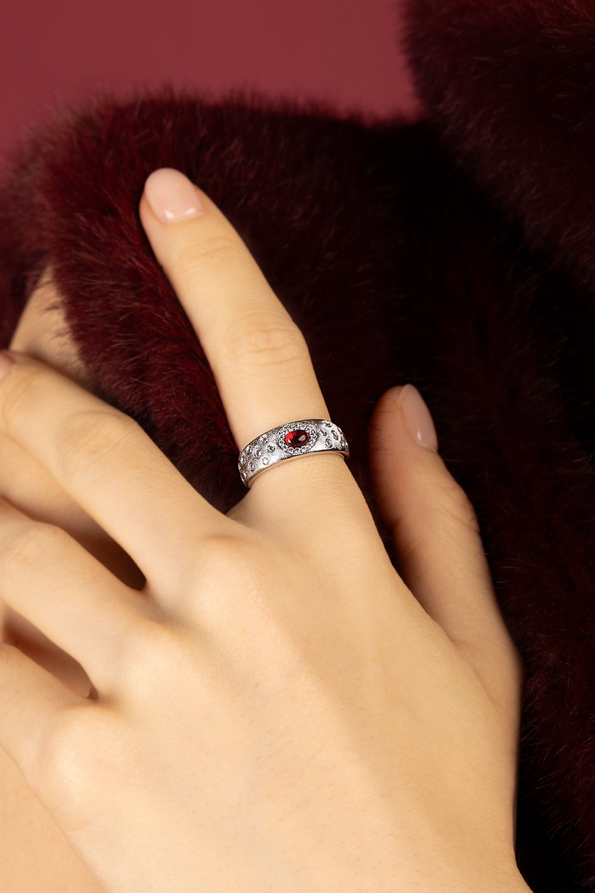 Femme portant la Bague APM, éclat rouge sur finition rhodium, élégance feutrée.