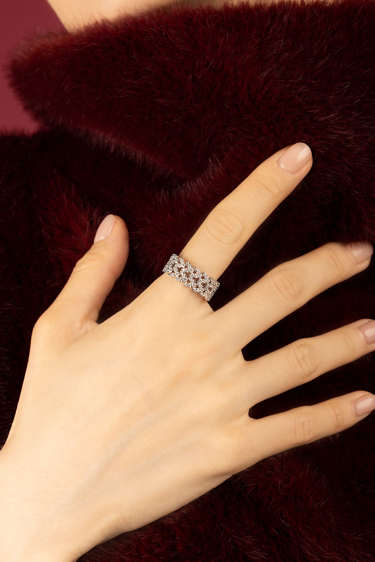 Femme portant une bague APM Monaco, éclat scintillant sur velours bordeaux.