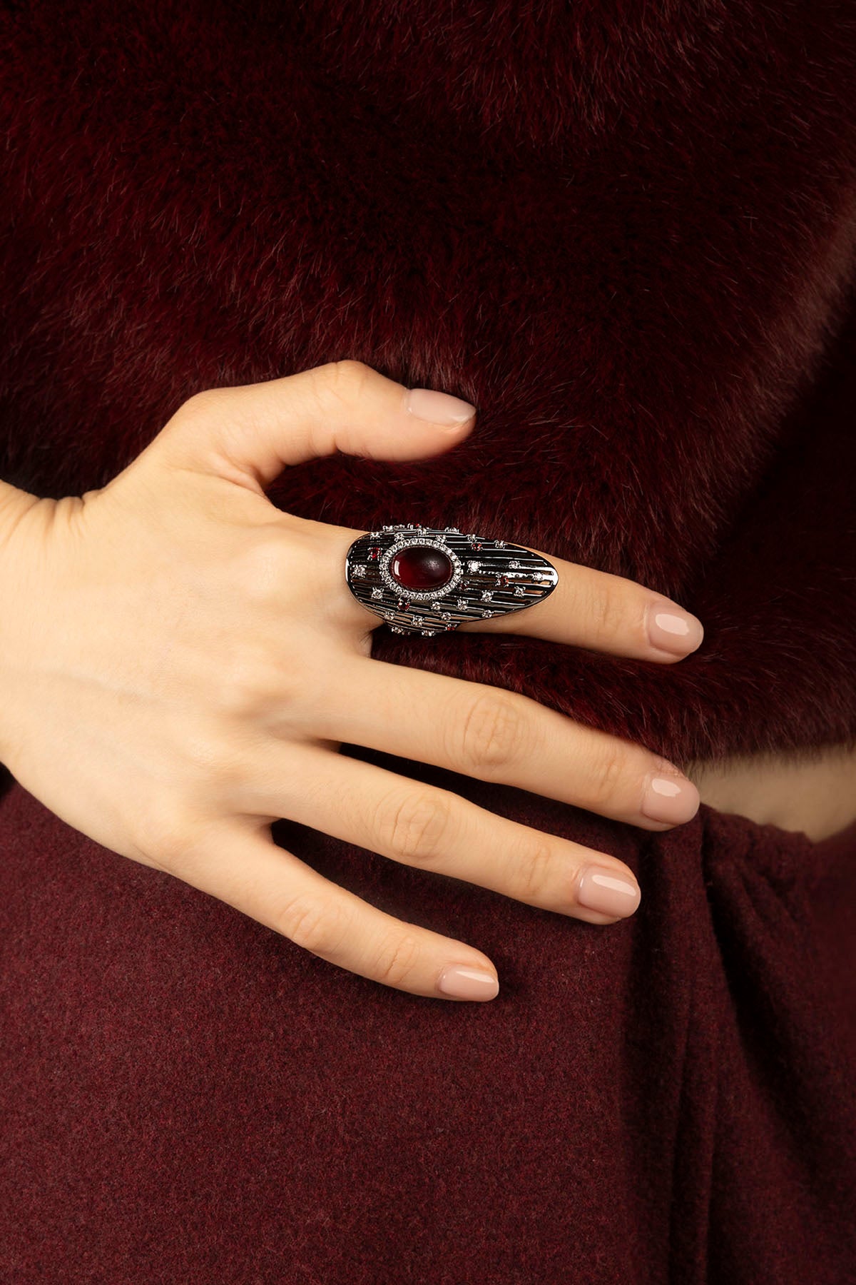 Femme portant la Bague APM, une allure couture ponctuée d'un rouge envoûtant.