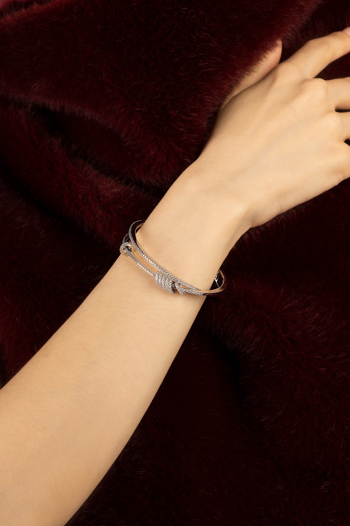 Femme portant le bracelet APM Monaco, éclat délicat sur bordeaux profond.