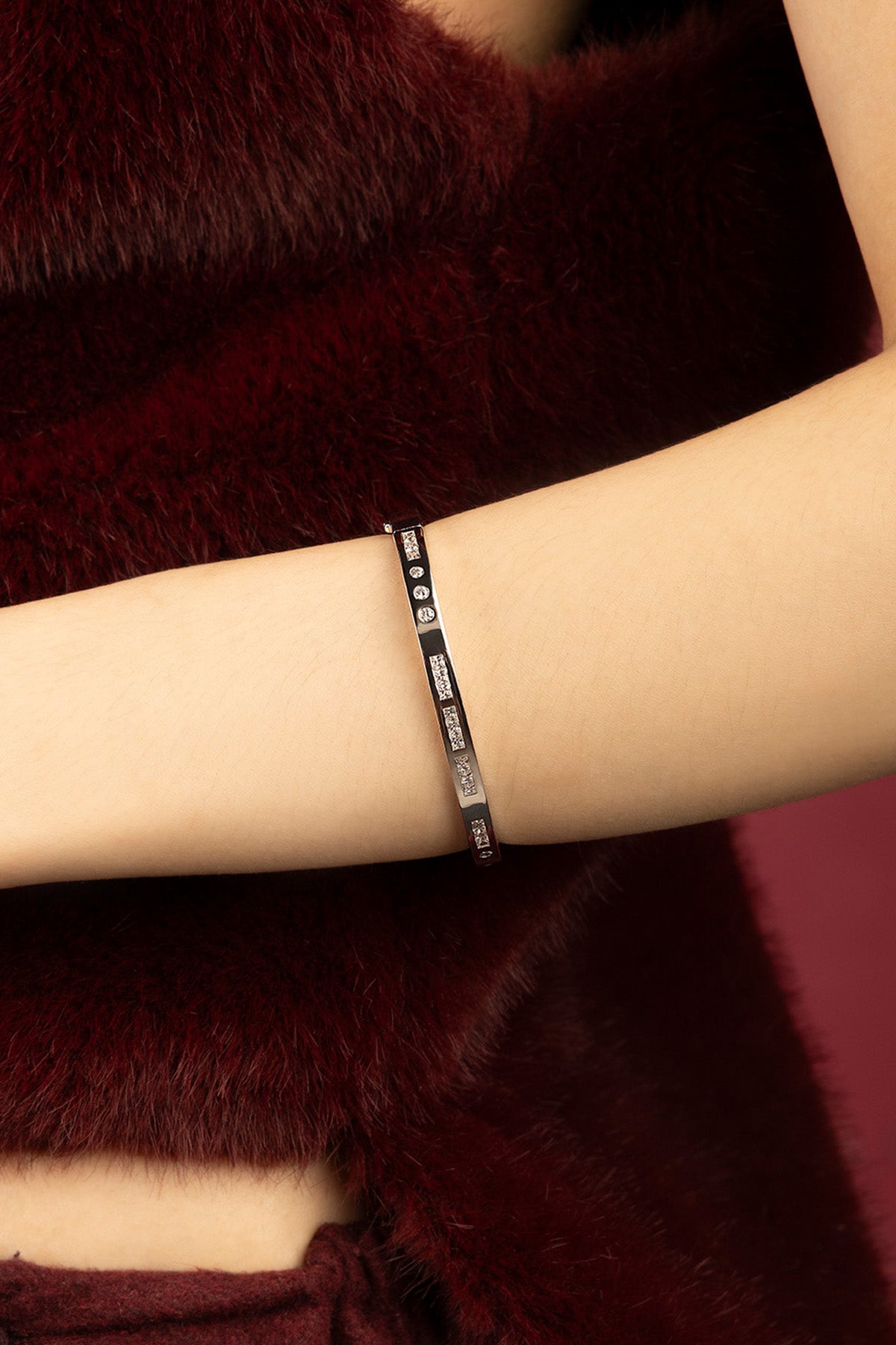 Woman wearing APM Morse Bracelet, une élégance codée sur fourrure bordeaux.