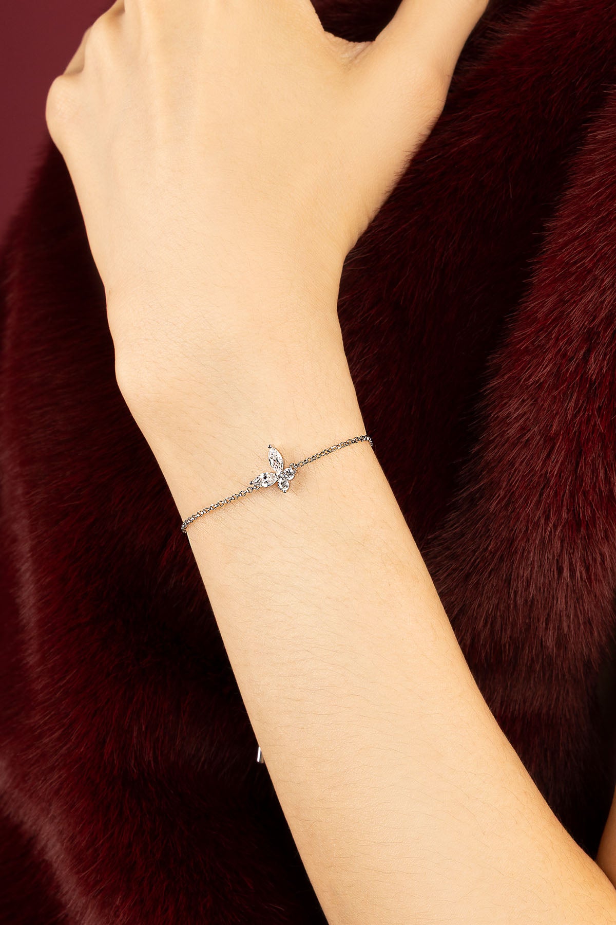 Femme portant le bracelet papillon APM Monaco, une envolée délicate sur fourrure bordeaux.