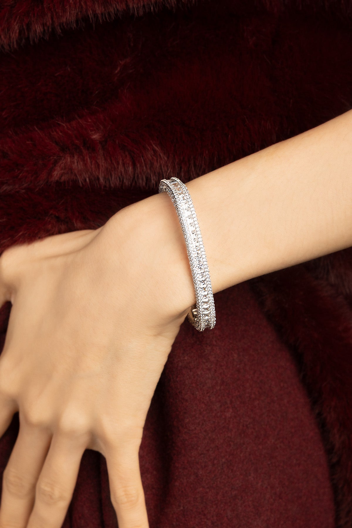 Femme portant le Bracelet APM Monaco, éclat scintillant sur fond de velours bordeaux.
