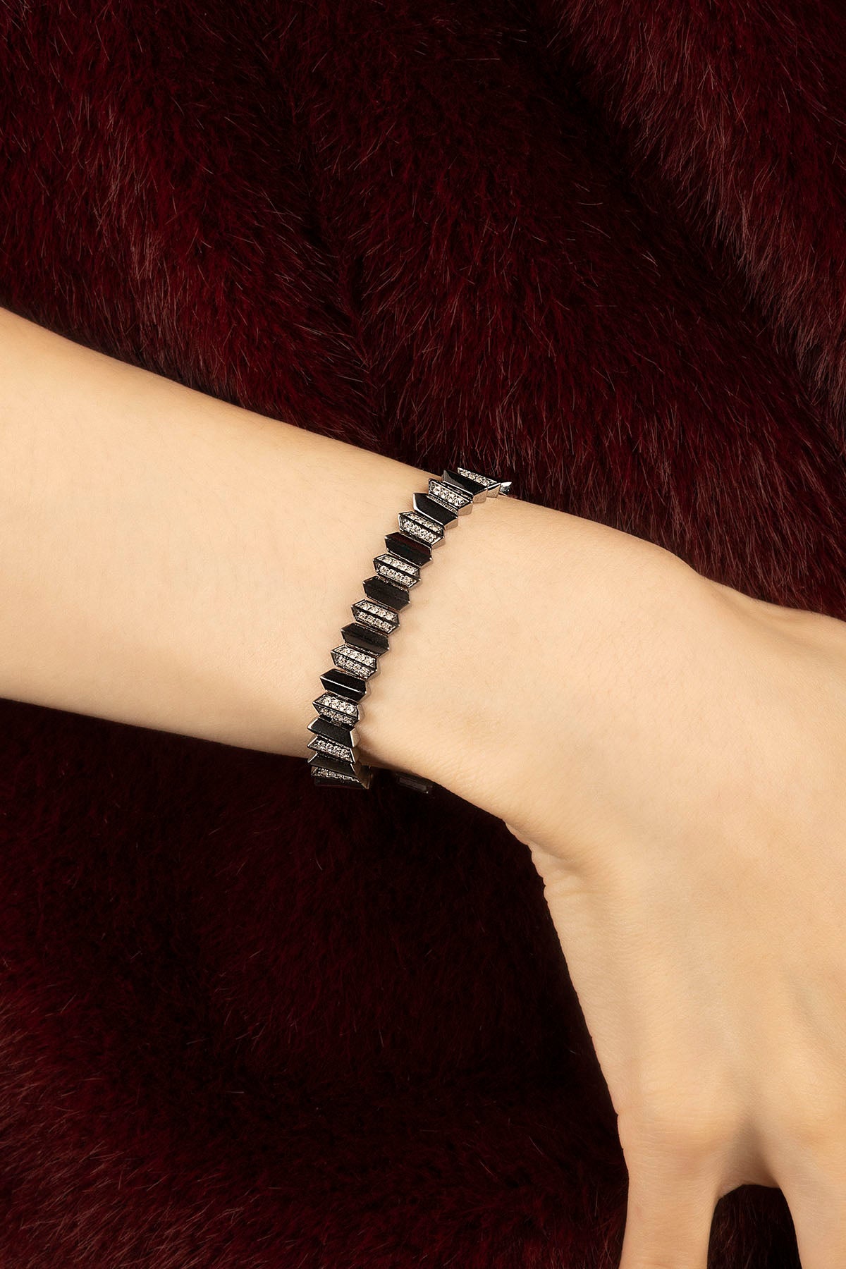 Femme portant le bracelet APM Monaco, une allure graphique et audacieuse sur fourrure bordeaux.