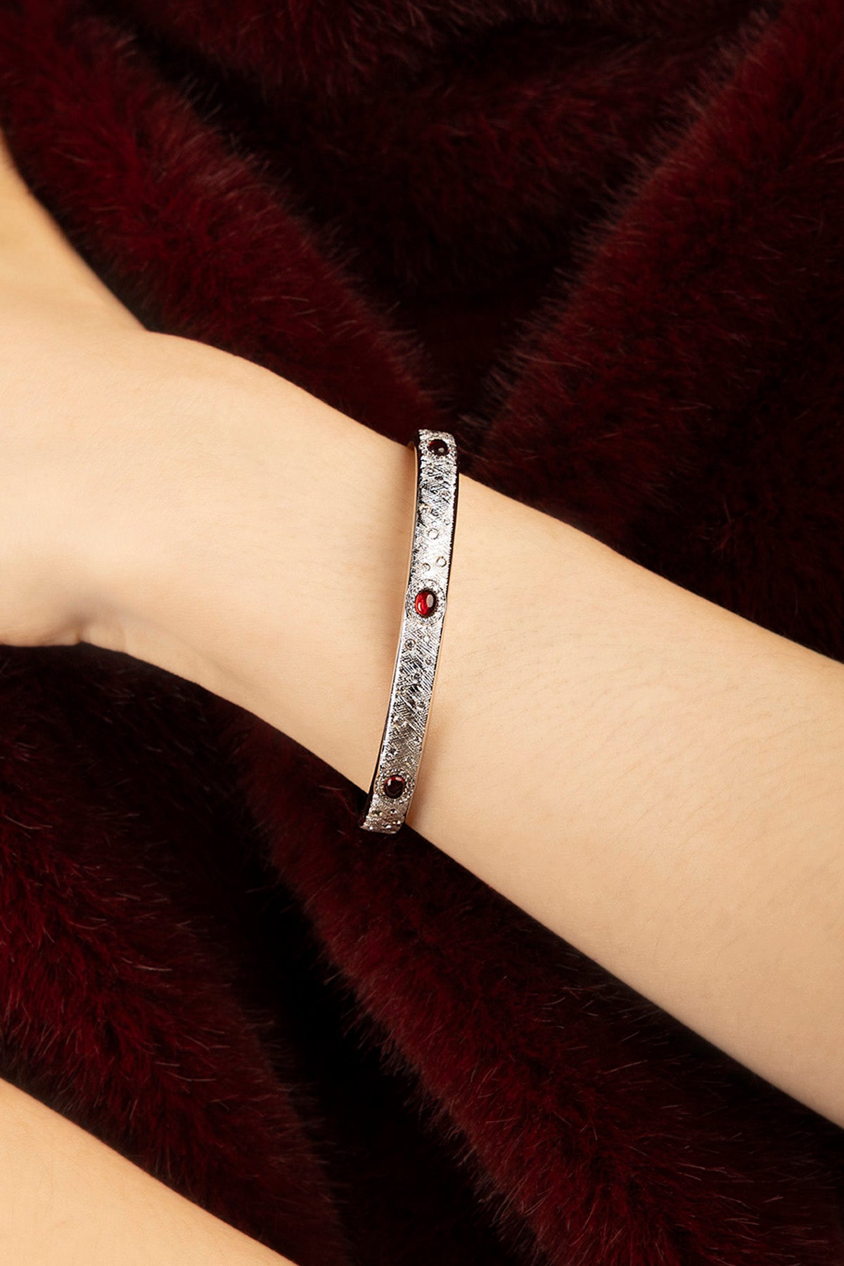 Femme portant le bracelet APM, une élégance discrète rehaussée d'éclats rouges profonds.