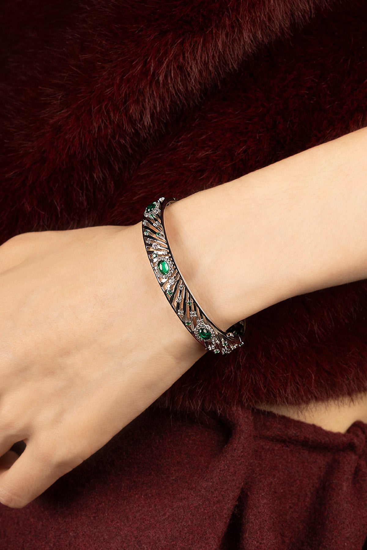 Femme portant le bracelet APM, éclats verts et finition rhodium, allure envoûtante.