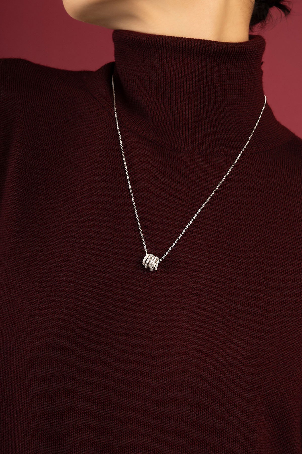 Femme portant le collier APM Monaco, une touche lumineuse sur un col bordeaux.