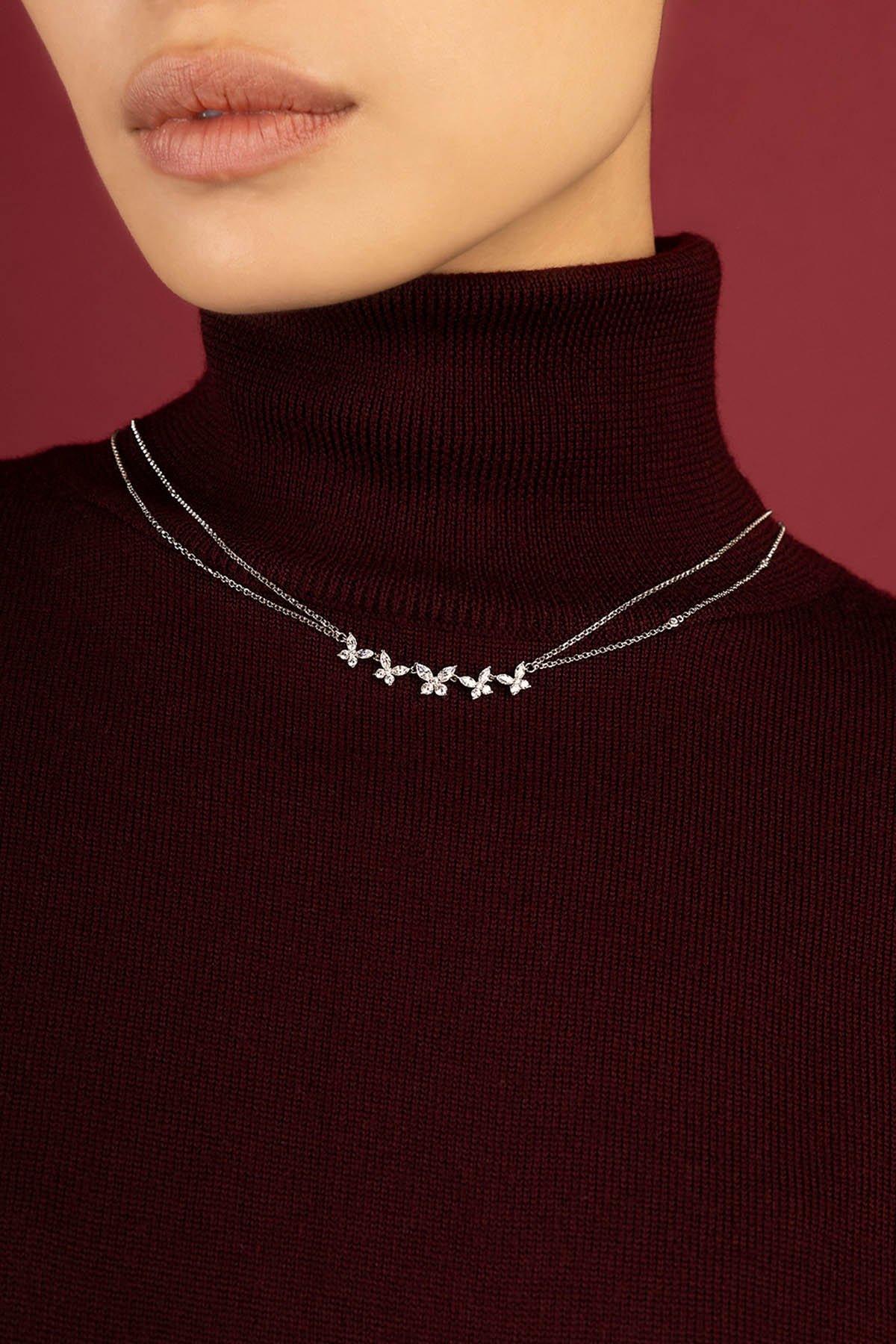 Femme portant le collier APM Monaco, une envolée florale délicate sur col bordeaux.