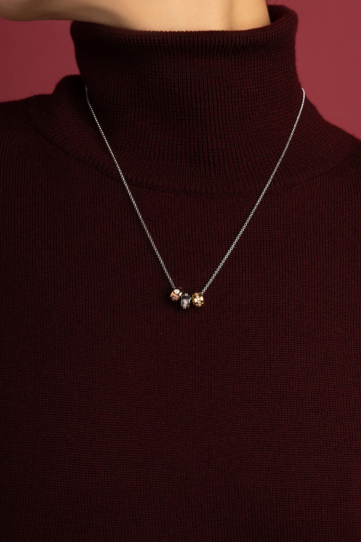 Femme portant le Collier APM, trio de charms tricolores, élégance discrète et moderne.