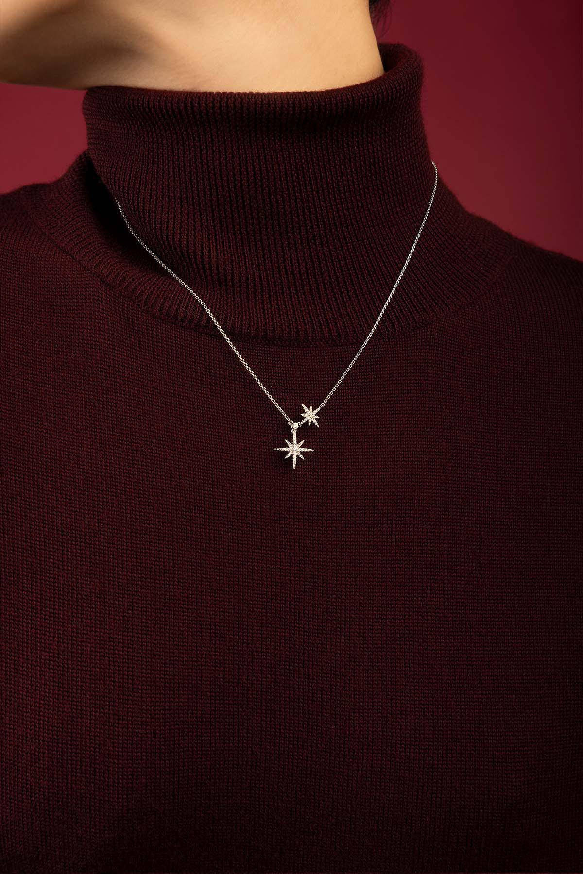 Femme portant le collier étoiles APM Monaco, éclat céleste sur bordeaux profond.