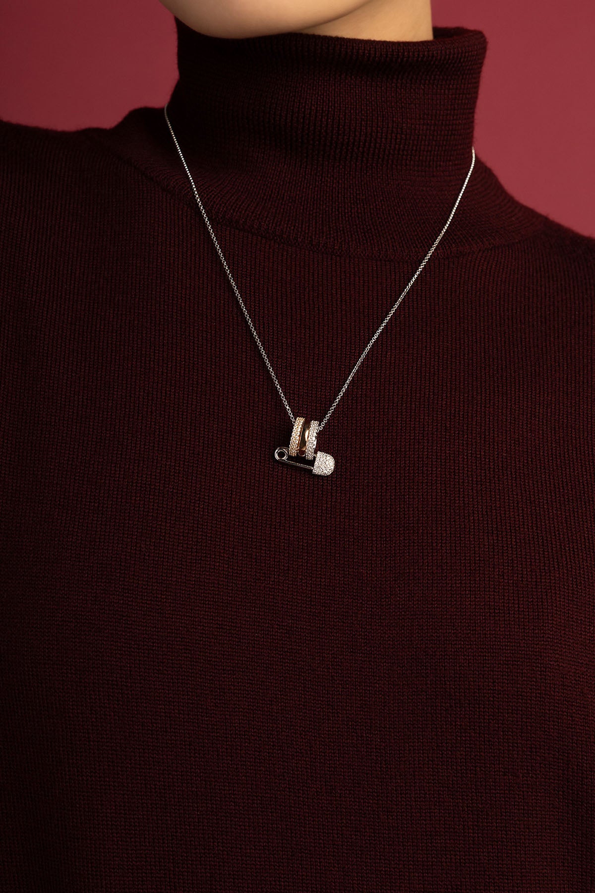 Femme portant le collier APM, épingle audacieuse et raffinée sur col bordeaux.