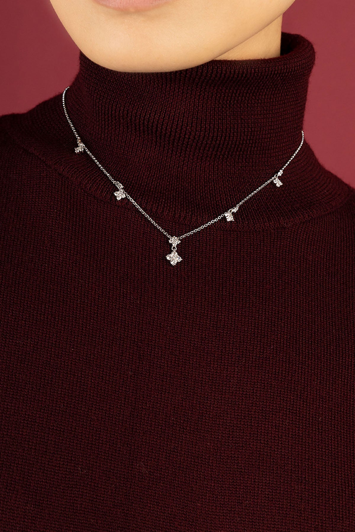 Woman wearing APM necklace, une touche scintillante sur col bordeaux.