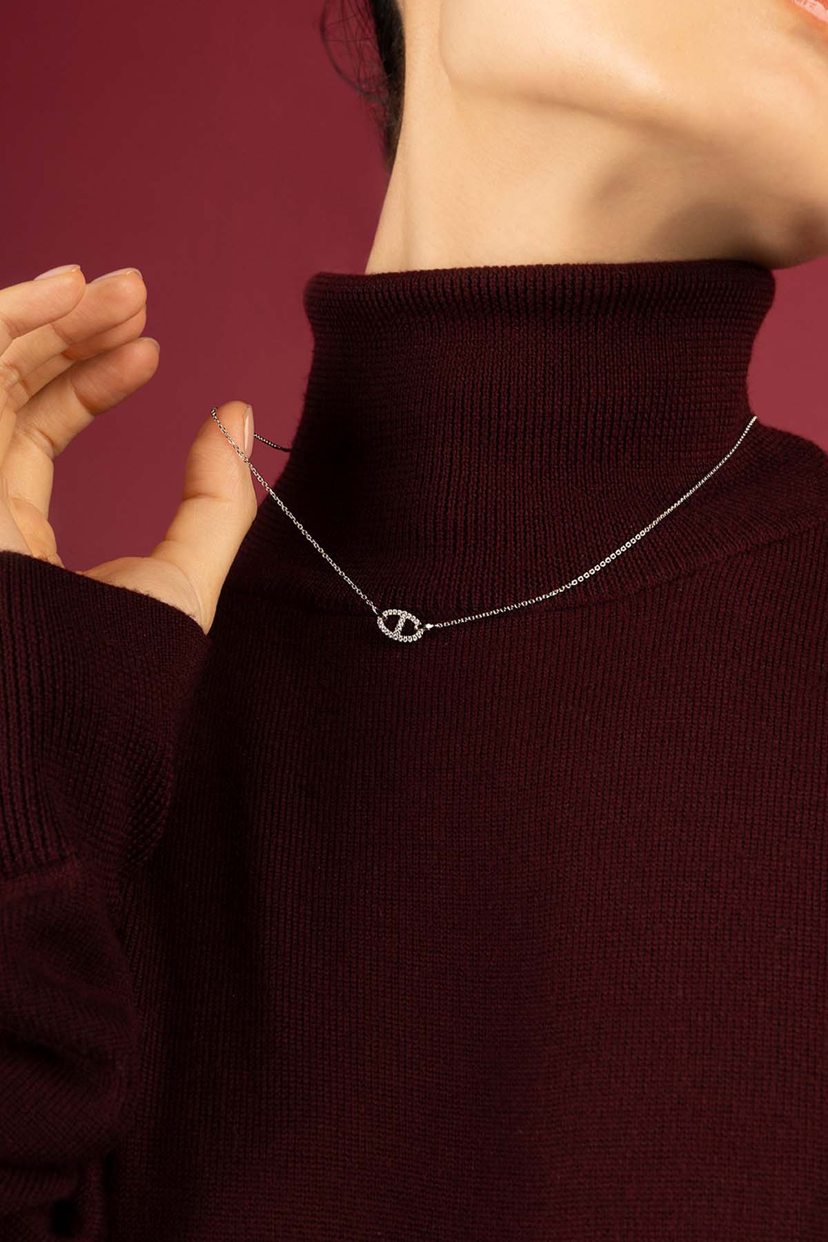 Femme portant le Collier APM Morse, une élégance discrète sur bordeaux profond.