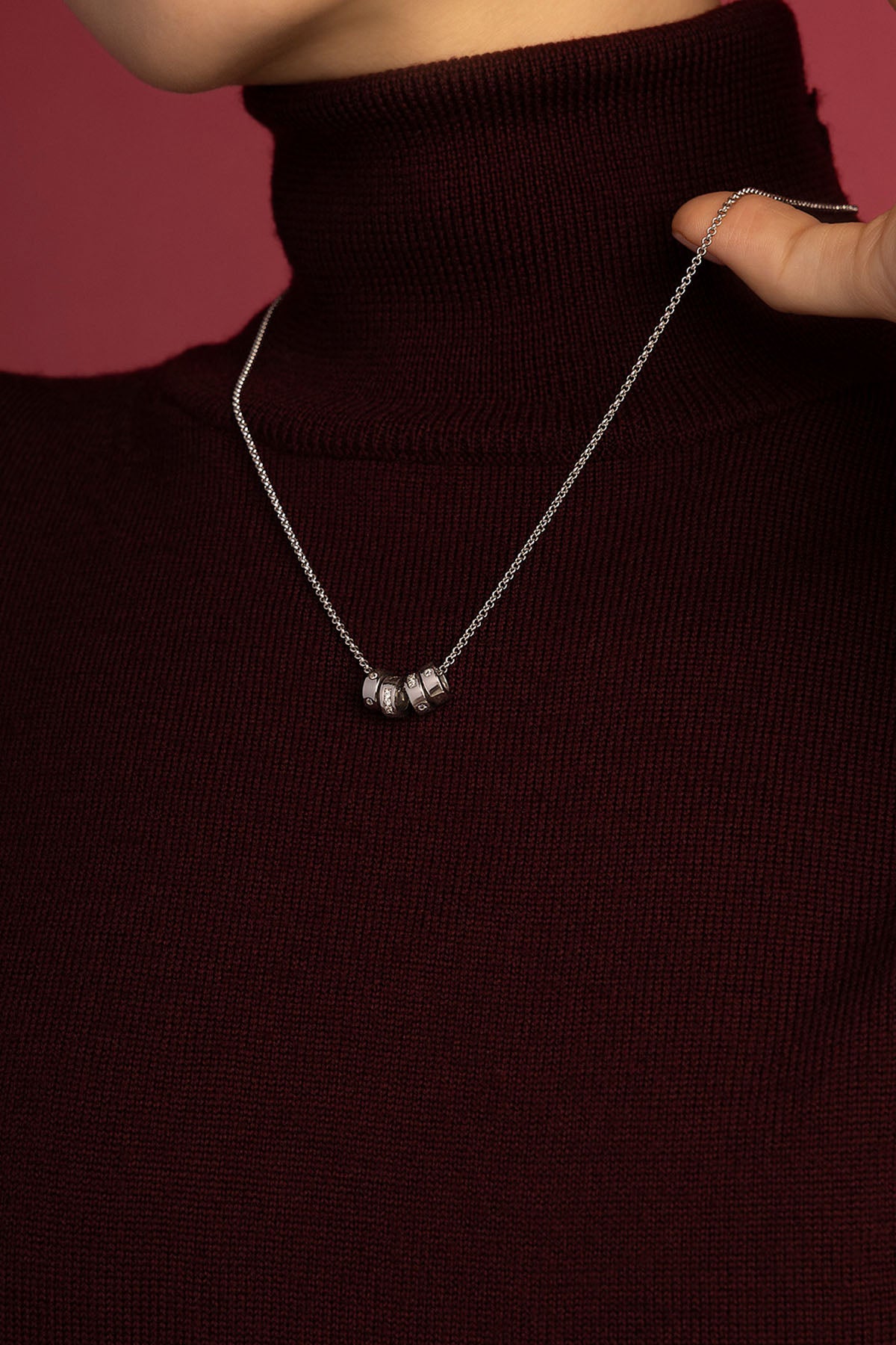 Femme portant le collier APM, éclat délicat sur un col roulé bordeaux.