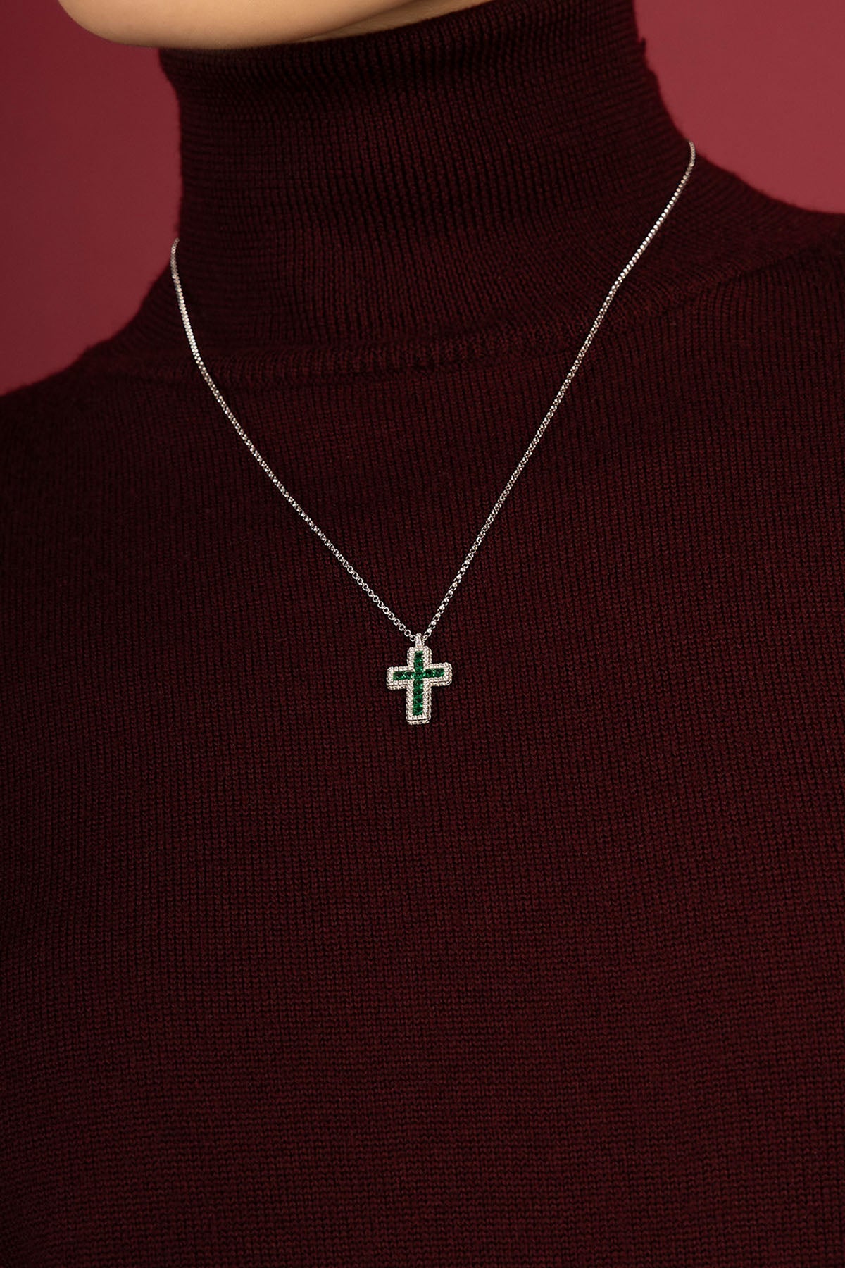 Femme portant le collier APM, croix verte lumineuse, élégance intemporelle et raffinée.