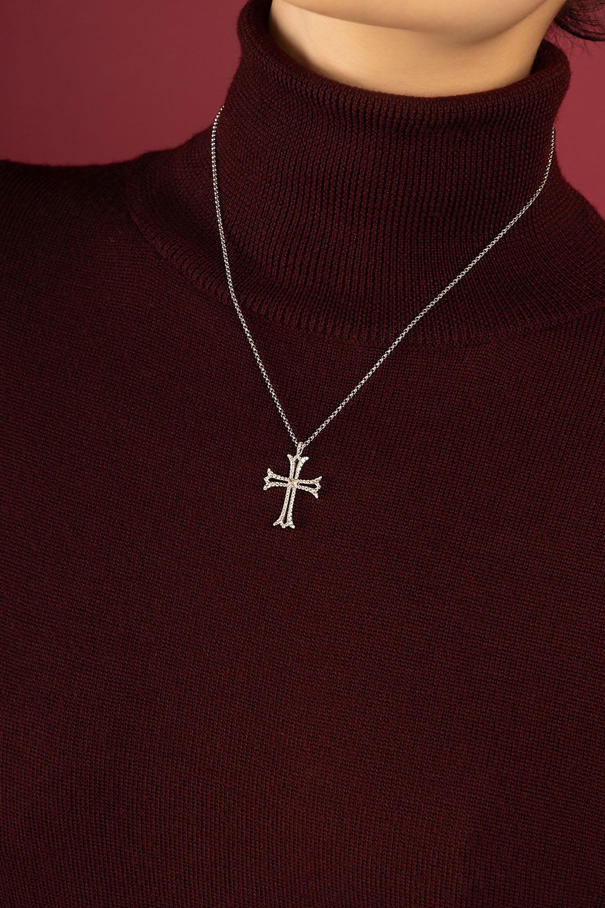 Femme portant le Collier Croix APM, une élégance intemporelle sur maille bordeaux.