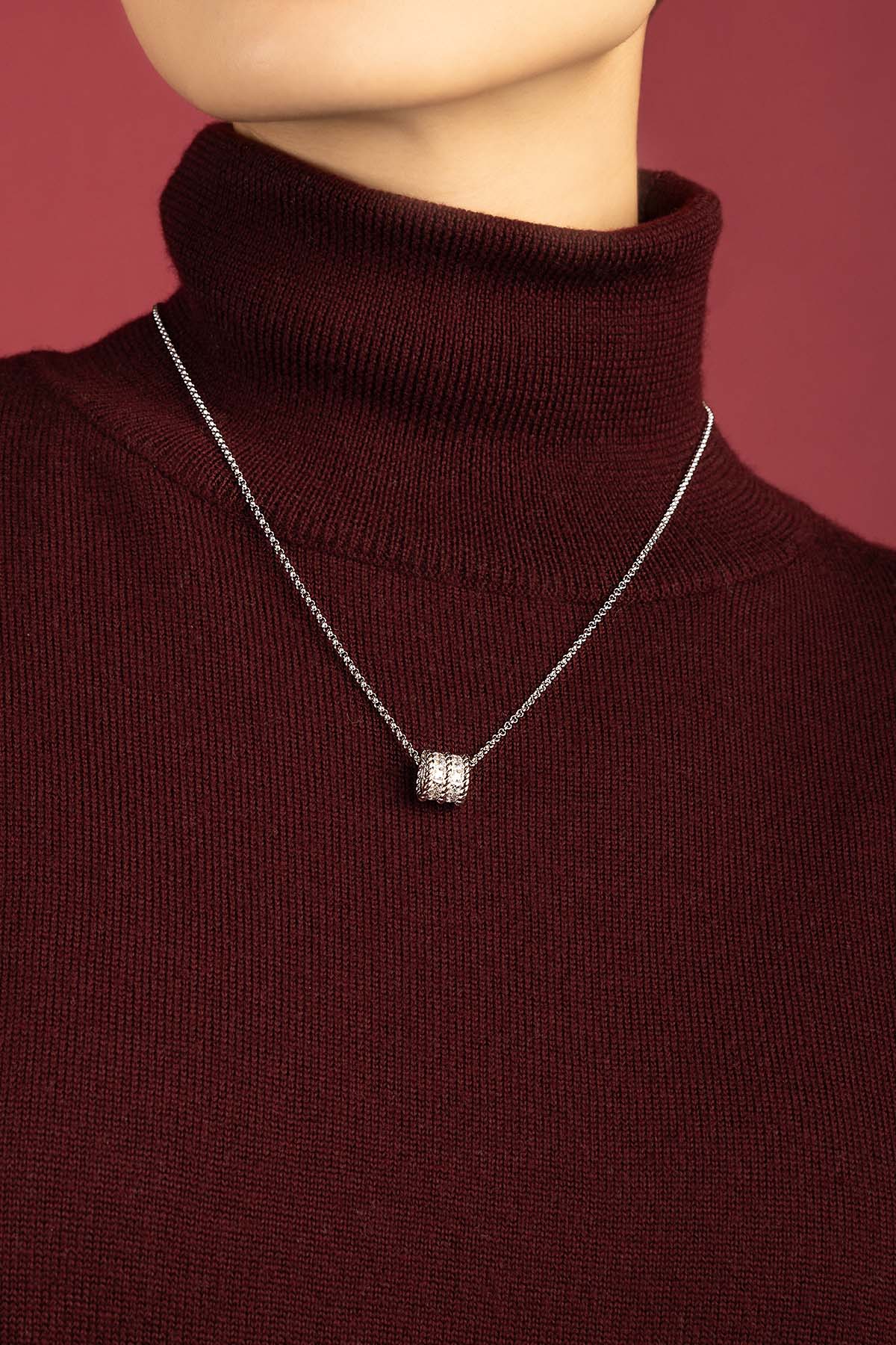 Femme portant le Collier APM Monaco, éclat délicat sur un col roulé bordeaux.