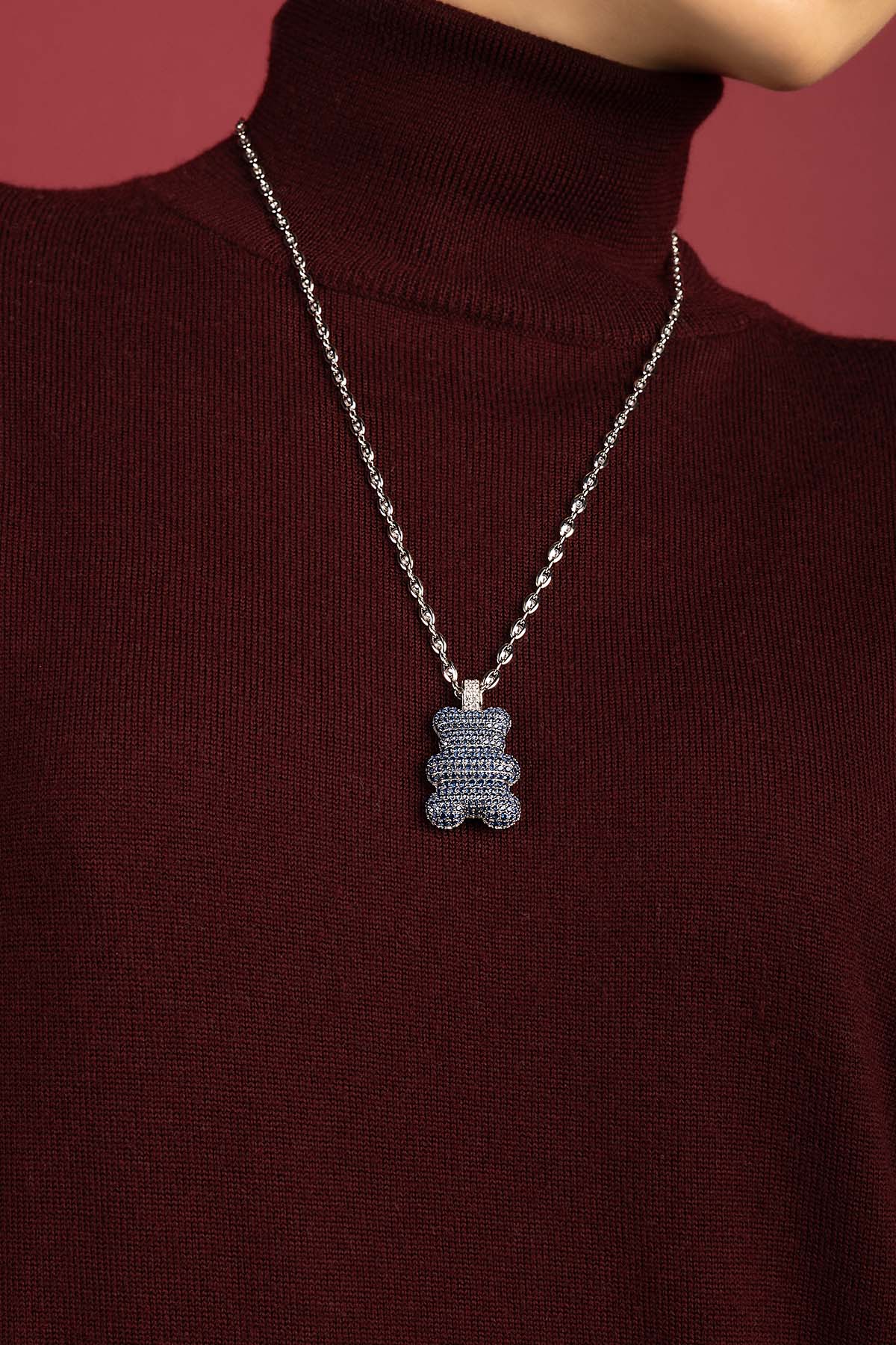 Femme portant le collier APM Yumi Bear, une touche ludique et chic sur maille bordeaux.