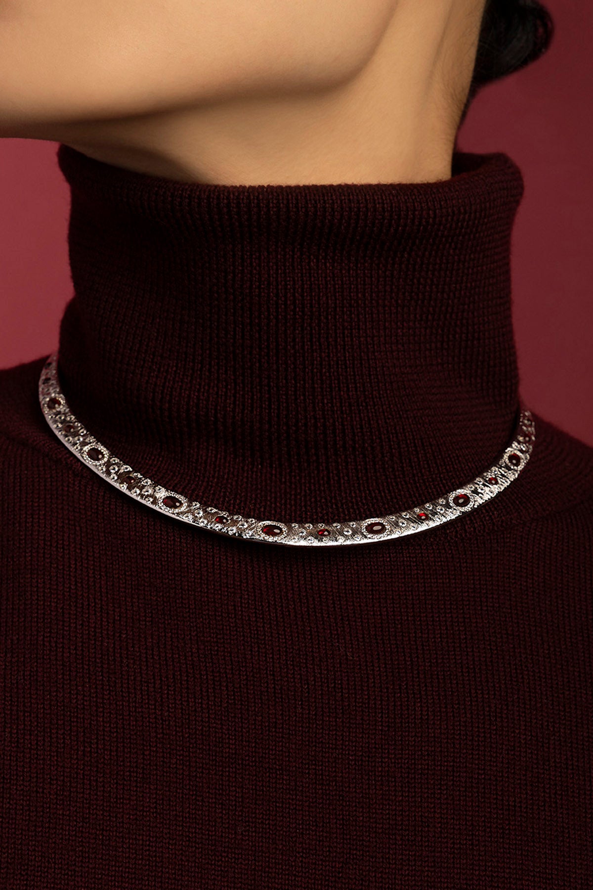 Femme portant le Collier APM Monaco, éclat rhodium ponctué de rouge, élégance hivernale.