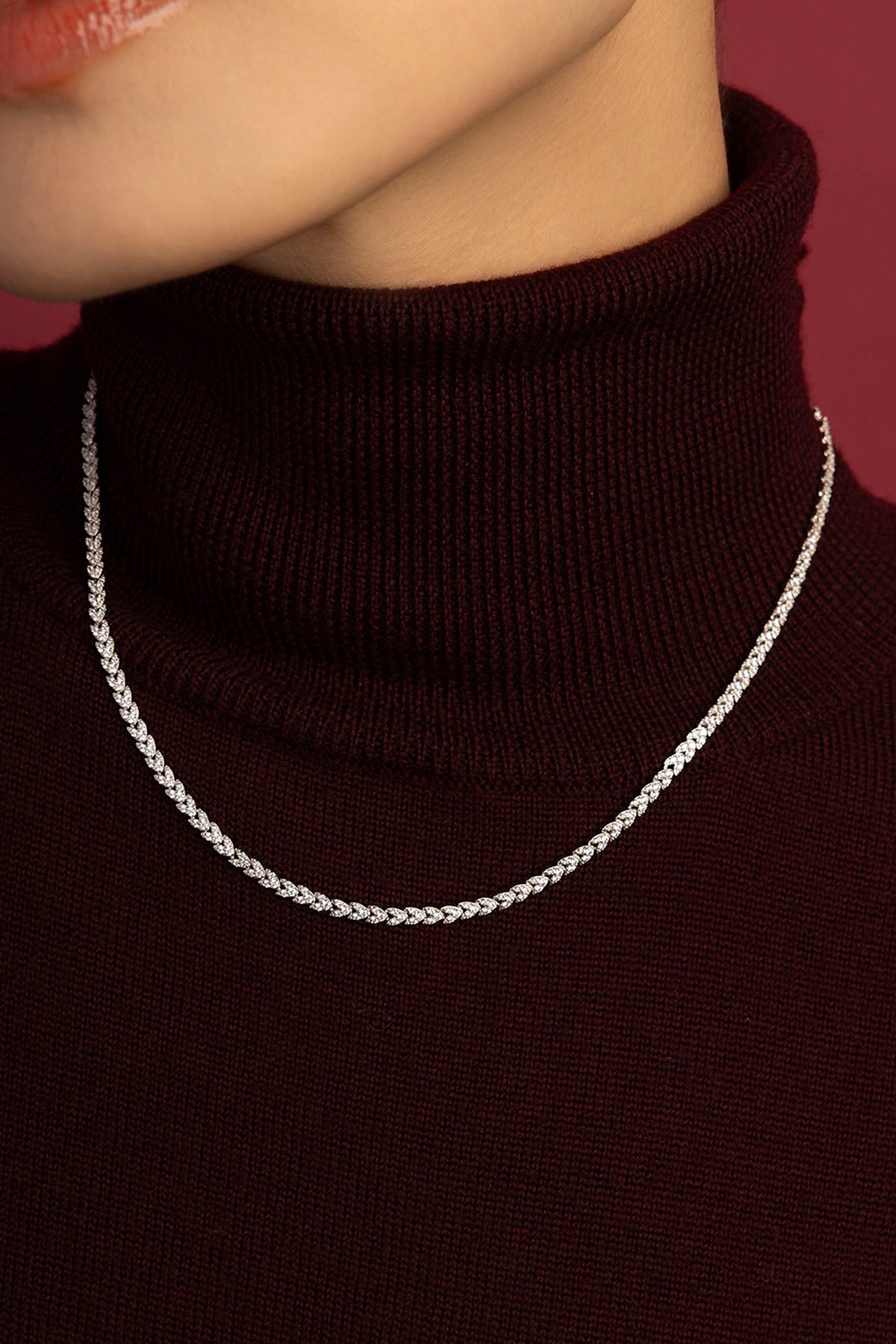 Femme portant le collier APM, éclat scintillant sur un col roulé bordeaux.