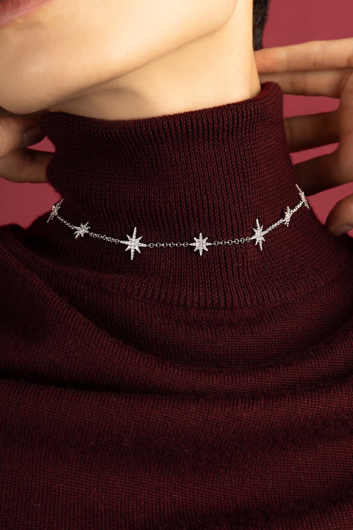 Femme portant un collier APM Météorites, une constellation lumineuse posée sur le col bordeaux.