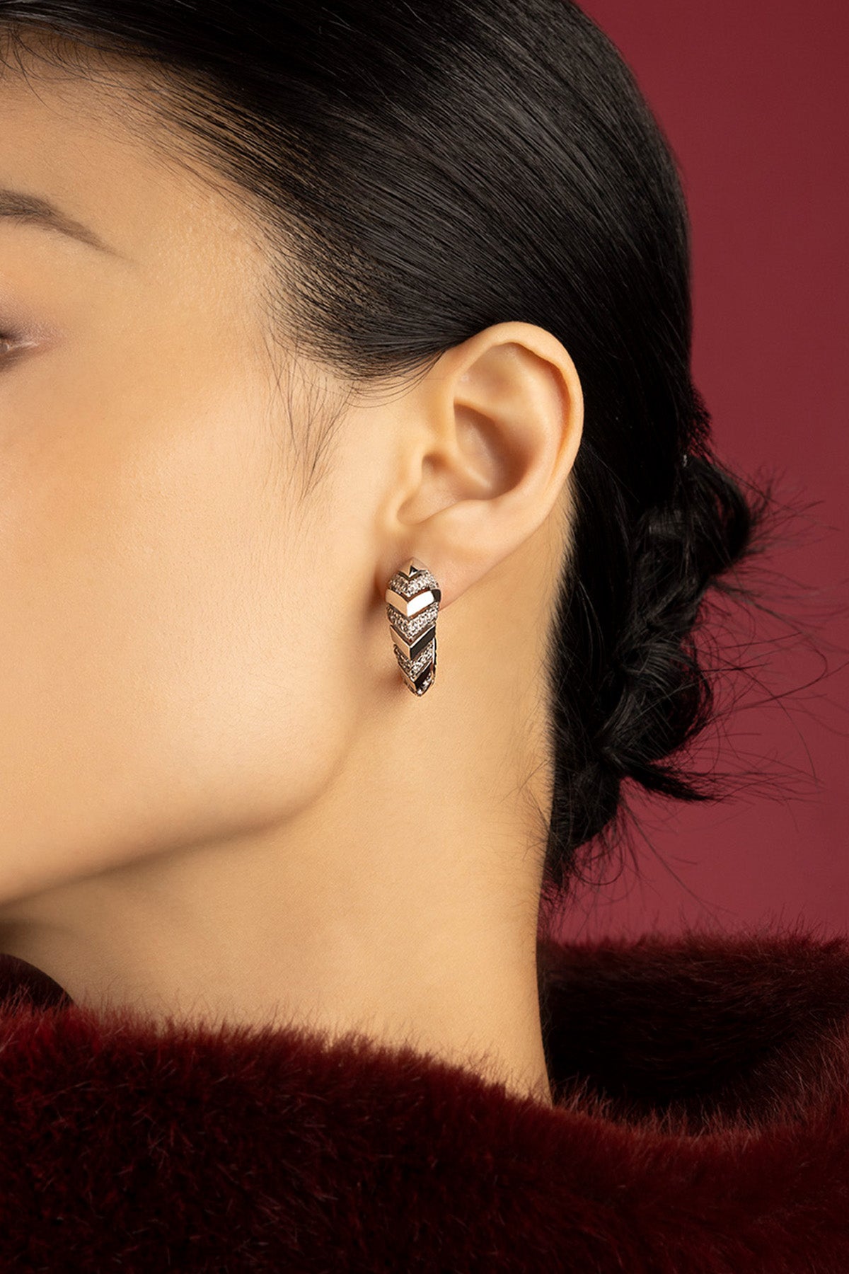 Femme portant les Boucles d'Oreilles APM, une allure chevron audacieuse et lumineuse.