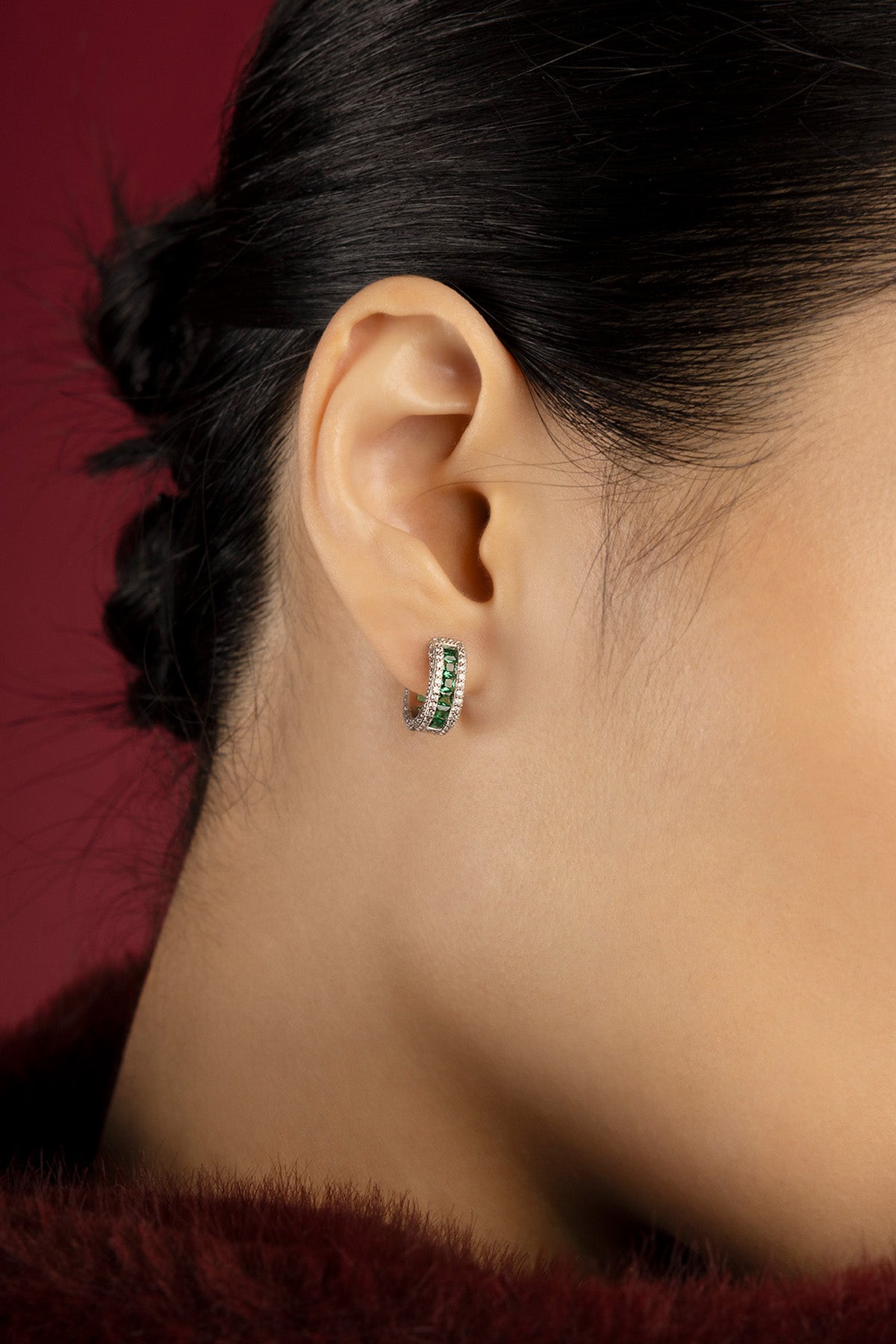 Femme portant les créoles APM, éclat vert profond et finition rhodium, élégance intemporelle.