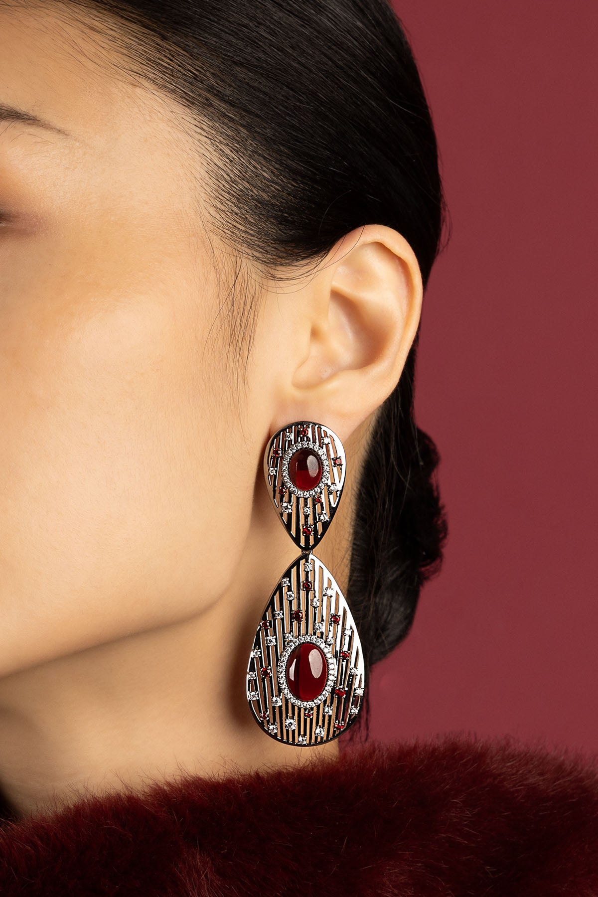 Woman wearing APM boucles d'oreilles, éclat rouge profond et allure couture intemporelle.
