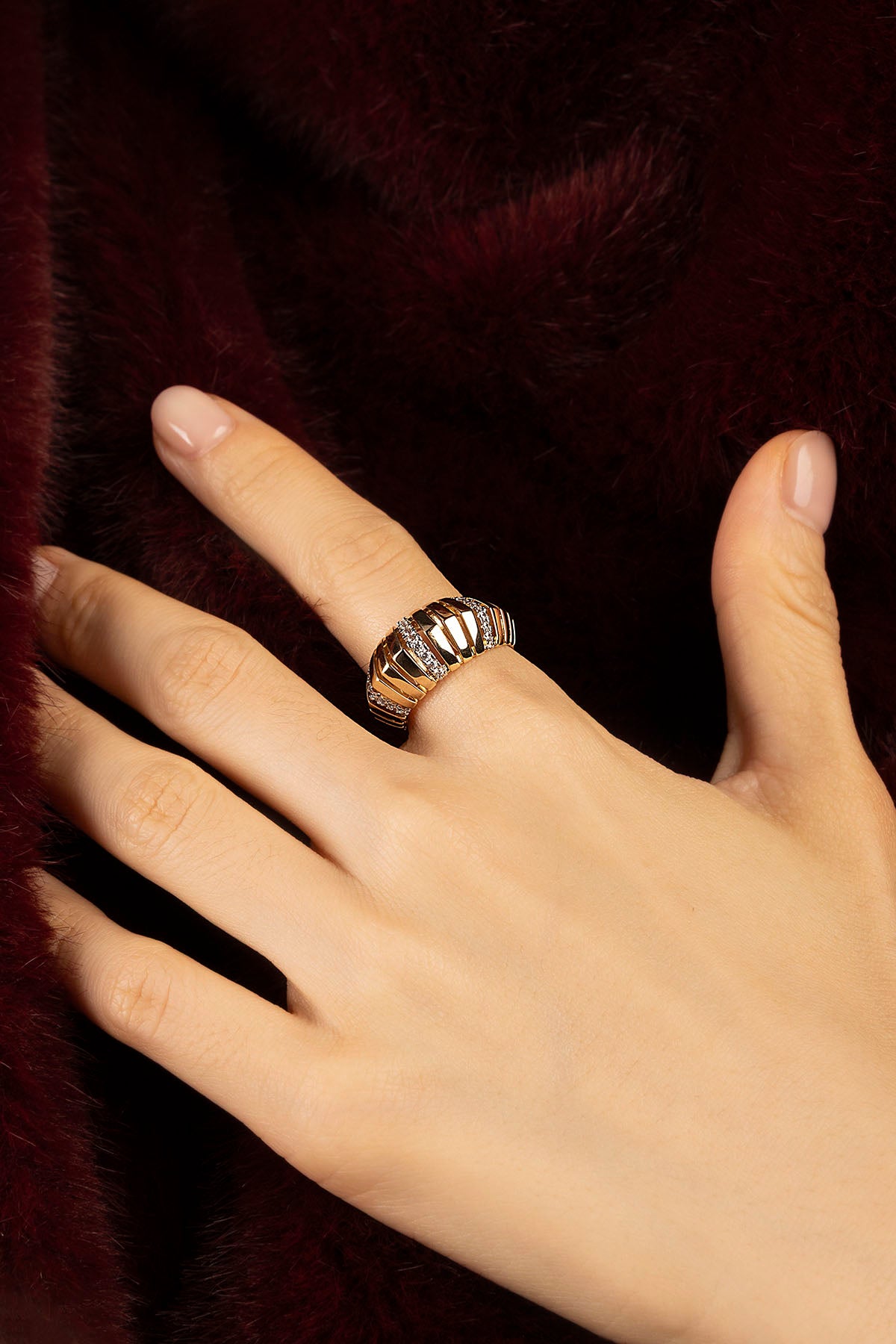 Femme portant la bague APM Monaco, éclat doré et allure sculpturale pour un hiver précieux.