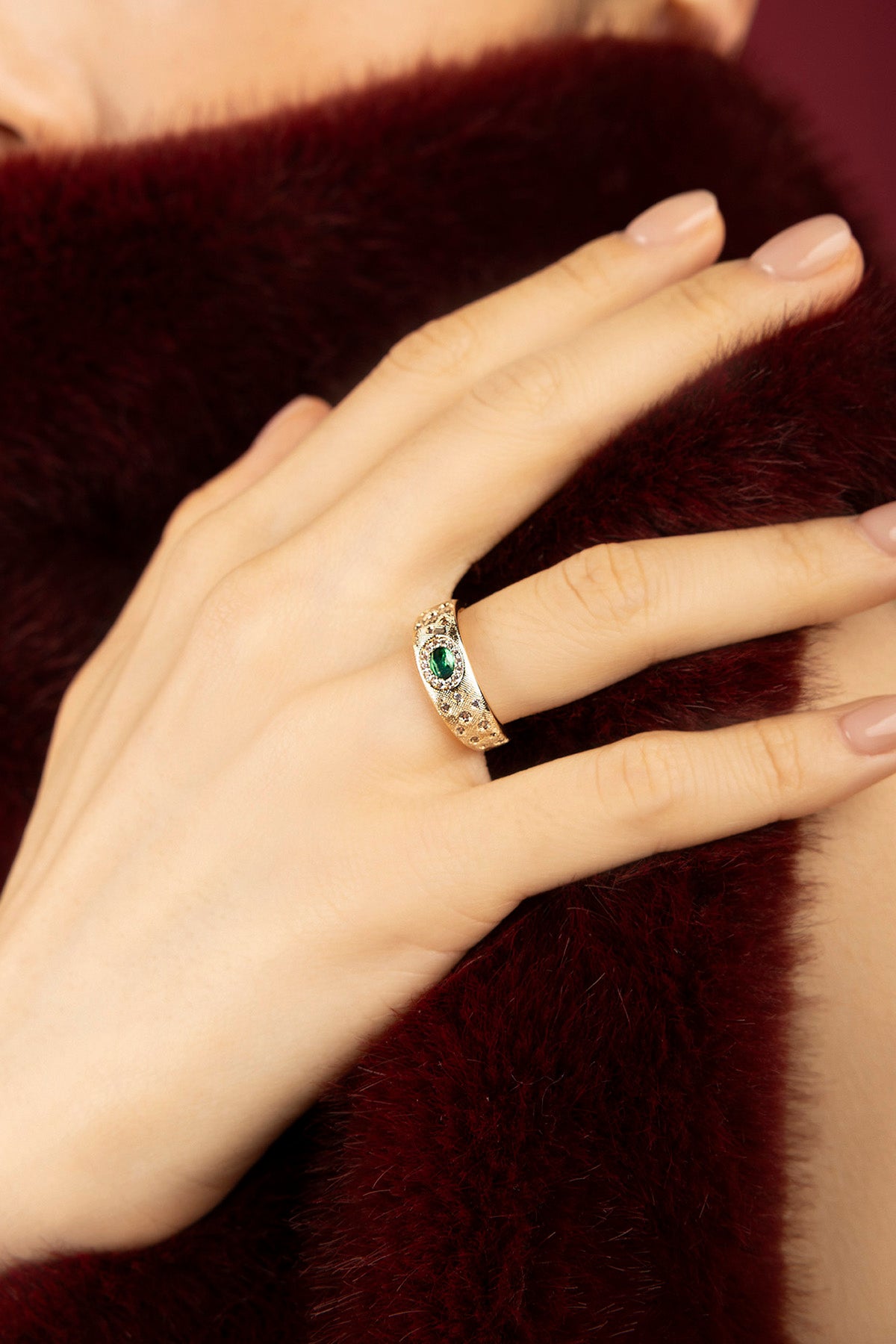 Femme portant la bague APM, éclat vert émeraude sur un hiver précieux.
