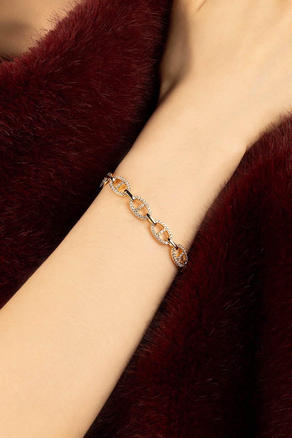 Femme portant le Bracelet APM Monaco, éclat doré et allure chic sur fourrure bordeaux.