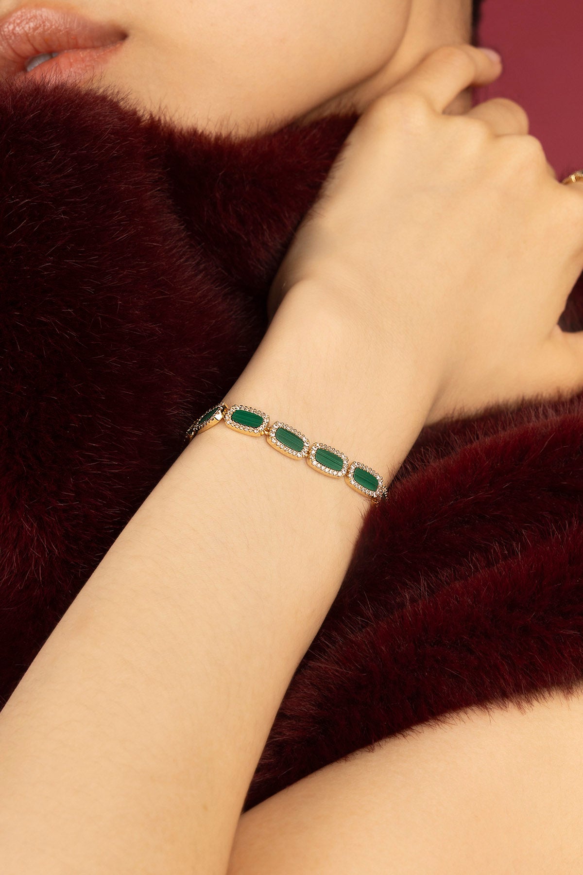Femme portant un bracelet APM, éclats verts et éclat doré, allure précieuse et raffinée.