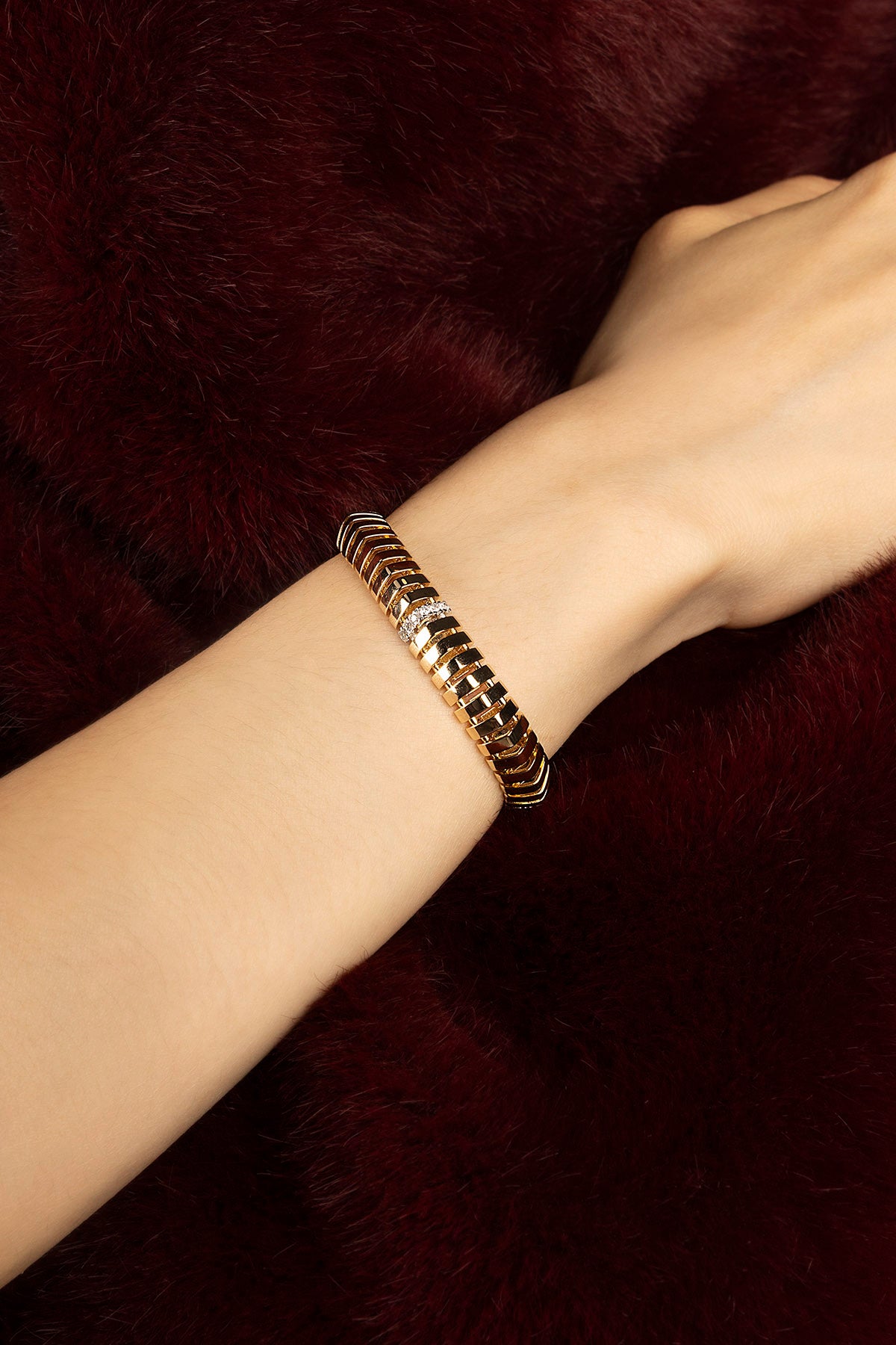 Femme portant le bracelet APM, éclat doré et allure sculpturale sur velours profond.