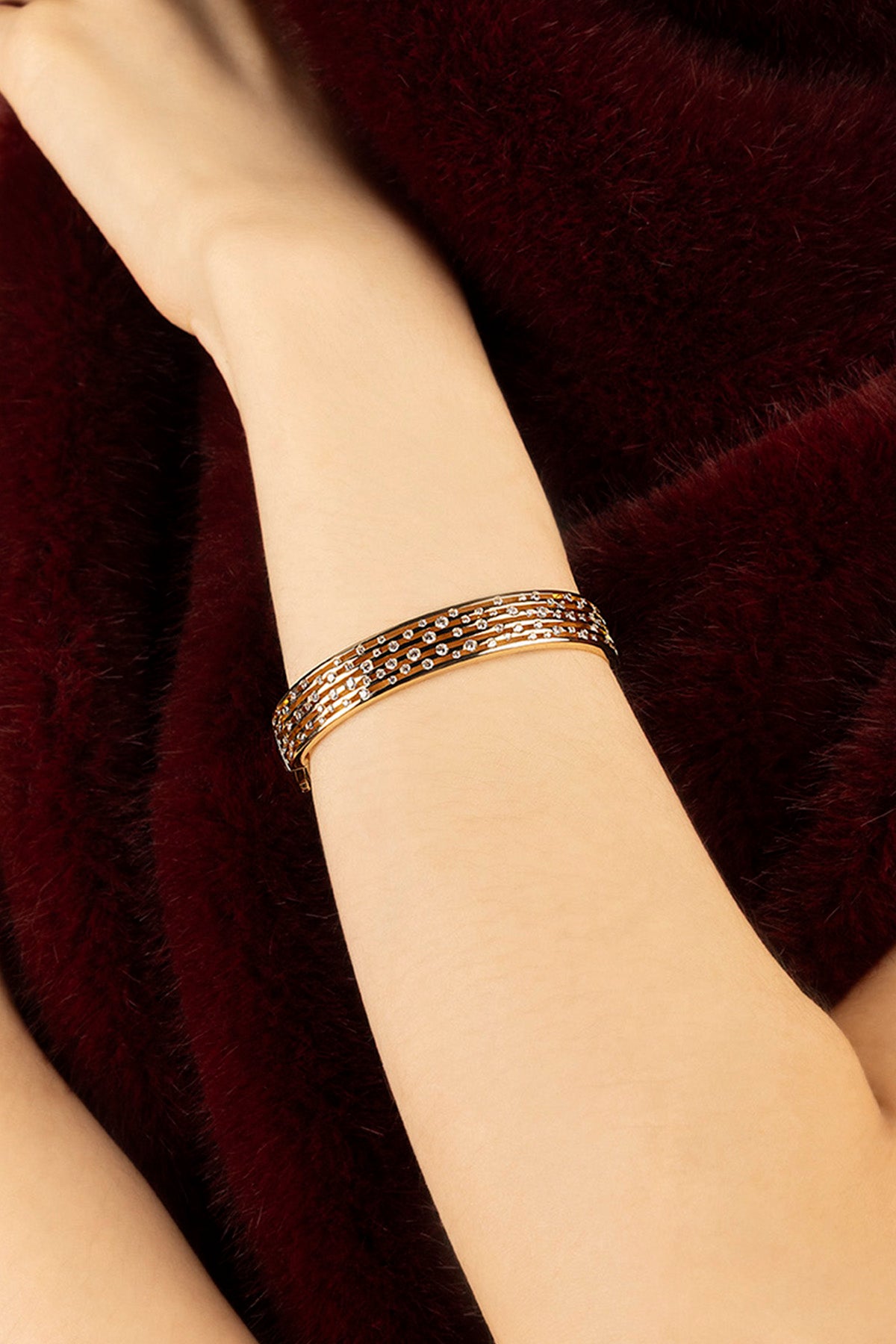 Femme portant le bracelet APM, éclat scintillant sur un velours bordeaux envoûtant.