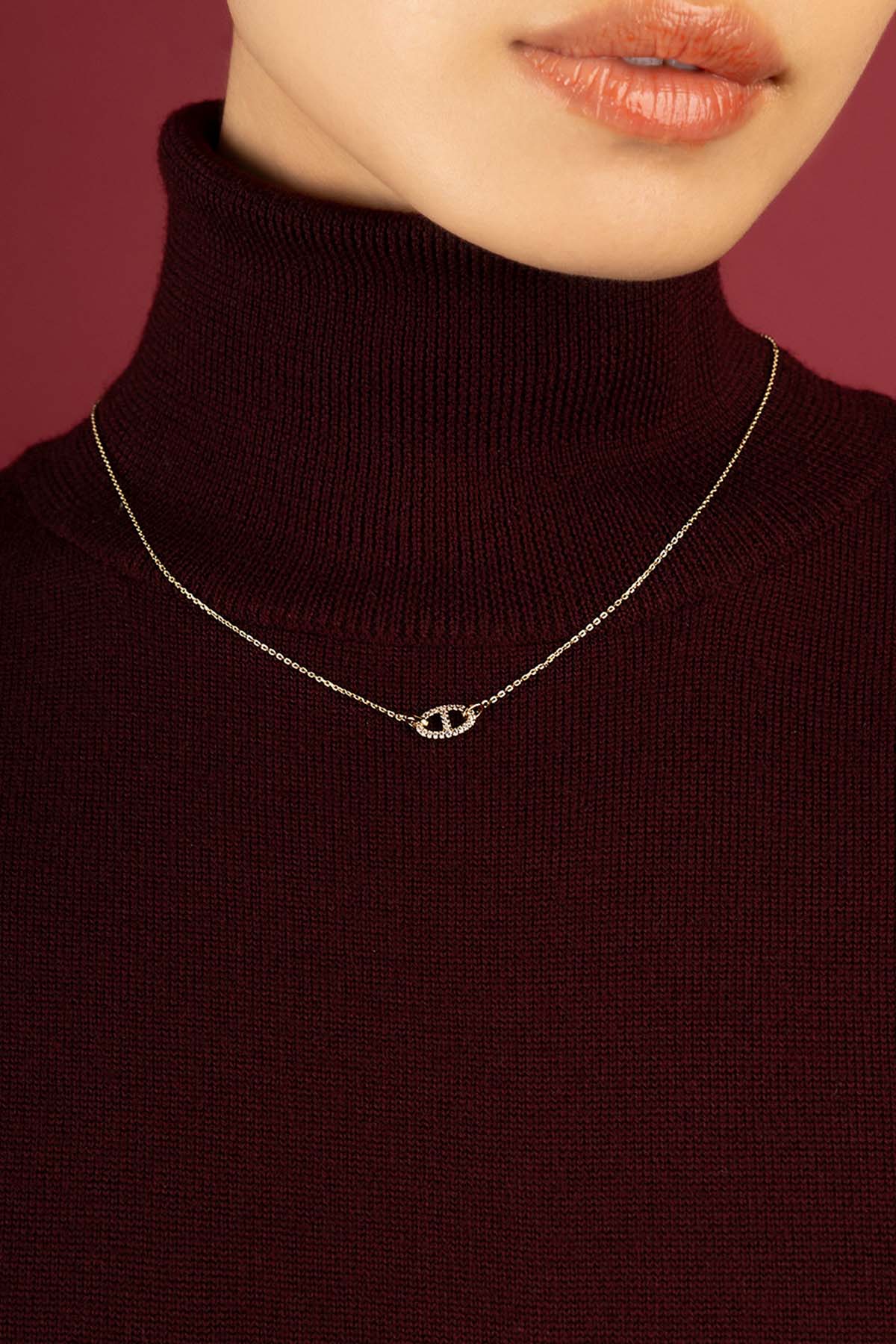 Femme portant le Collier Morse APM, une touche délicate sur un col bordeaux.