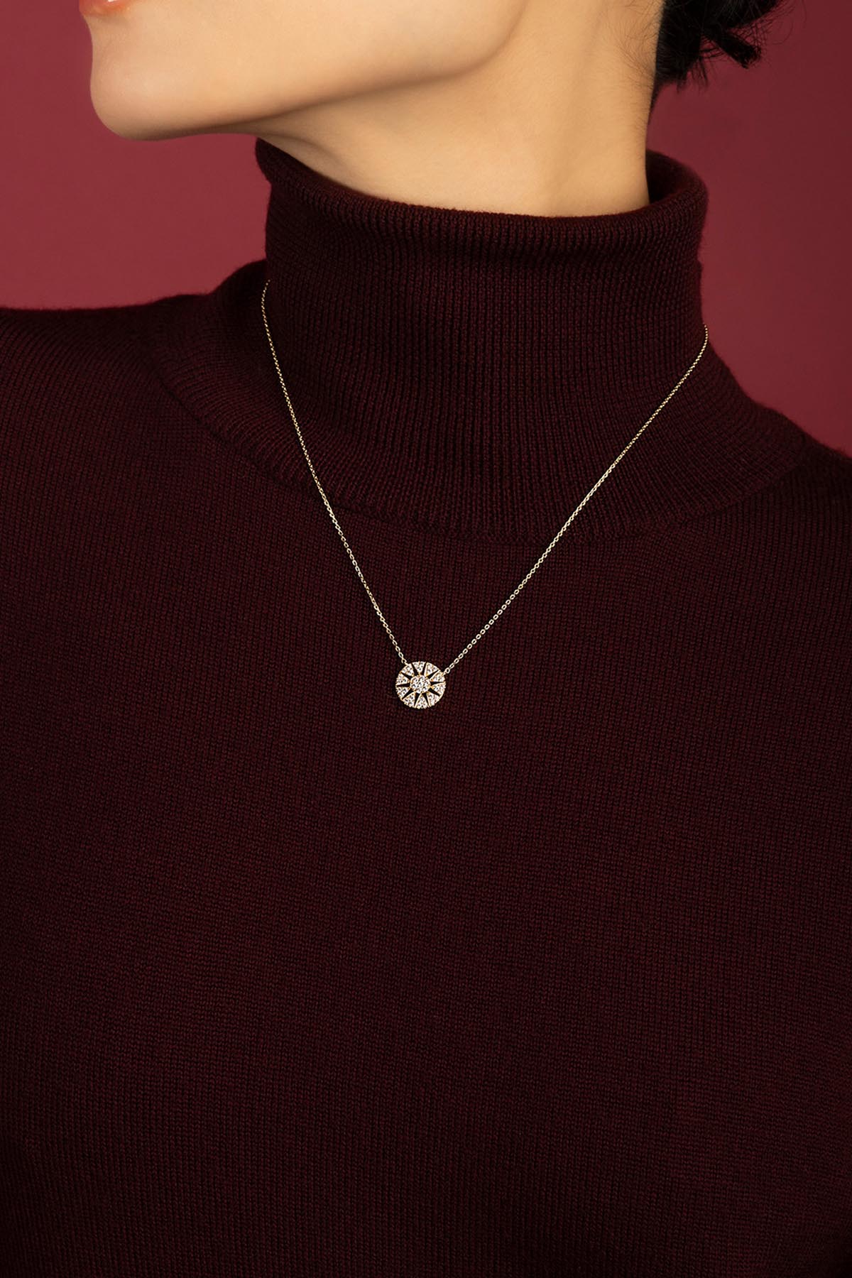 Femme portant le collier APM Monaco, une étoile lumineuse posée sur la laine bordeaux.