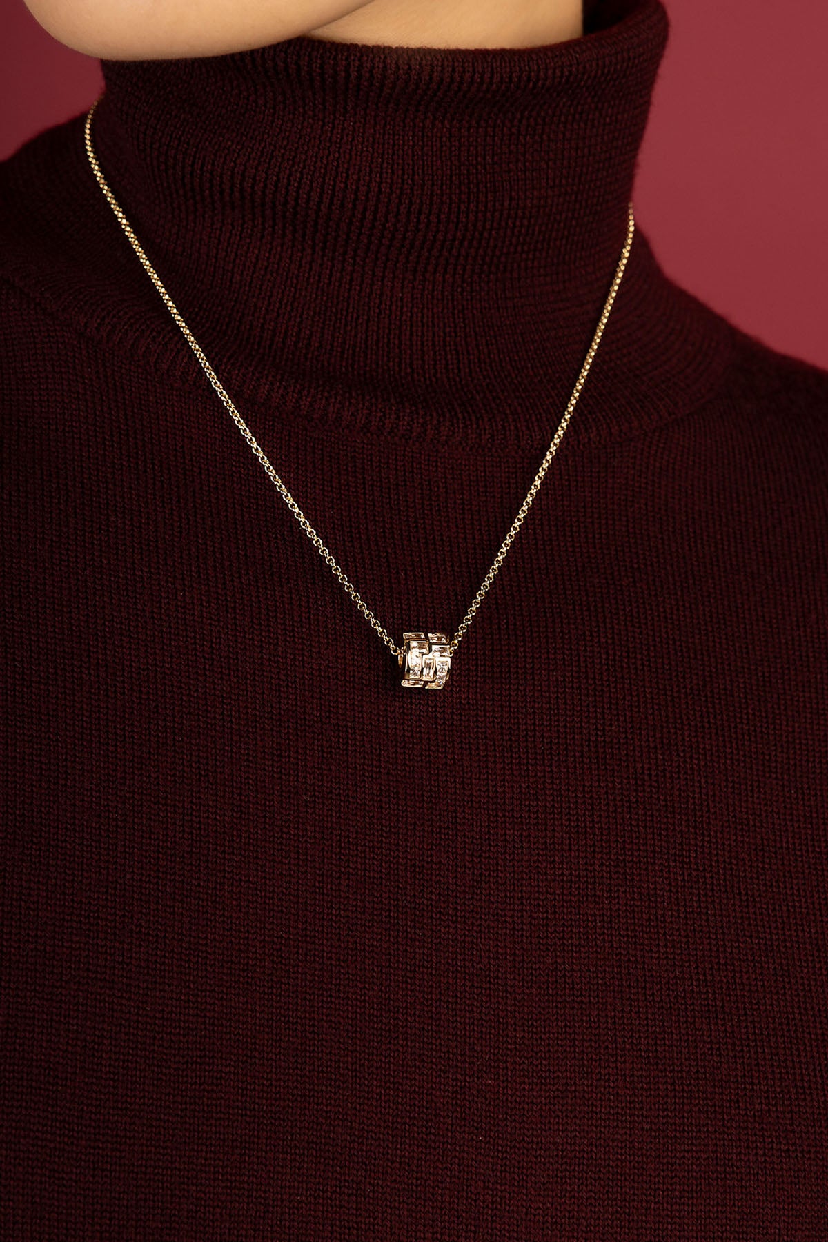 Femme portant le Collier APM Monaco, une élégance dorée sur bordeaux profond.