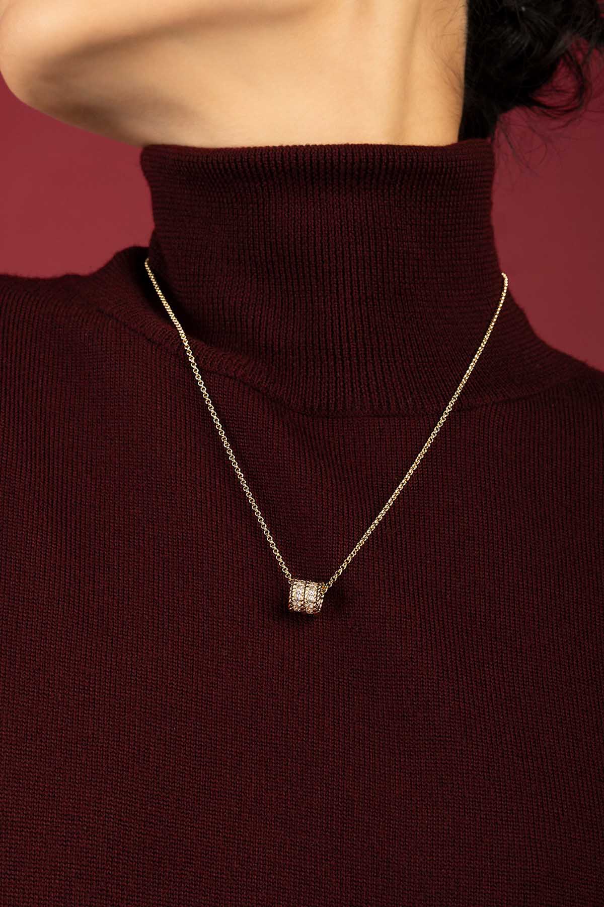 Femme portant un collier APM Monaco, éclat doré délicat sur bordeaux profond.