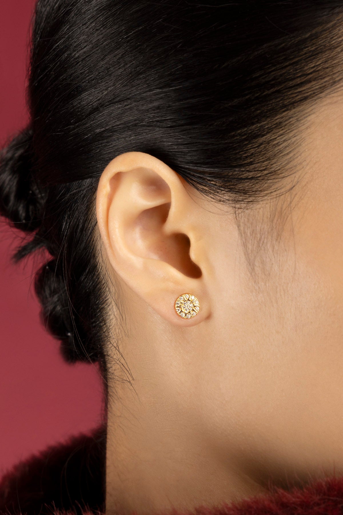 Femme portant les Boucles d'Oreilles Morse APM, une étoile lumineuse aux reflets dorés.