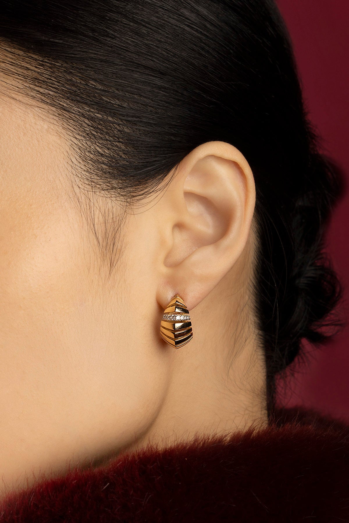 Femme portant les boucles d'oreilles APM, une allure sculpturale aux reflets dorés envoûtants.