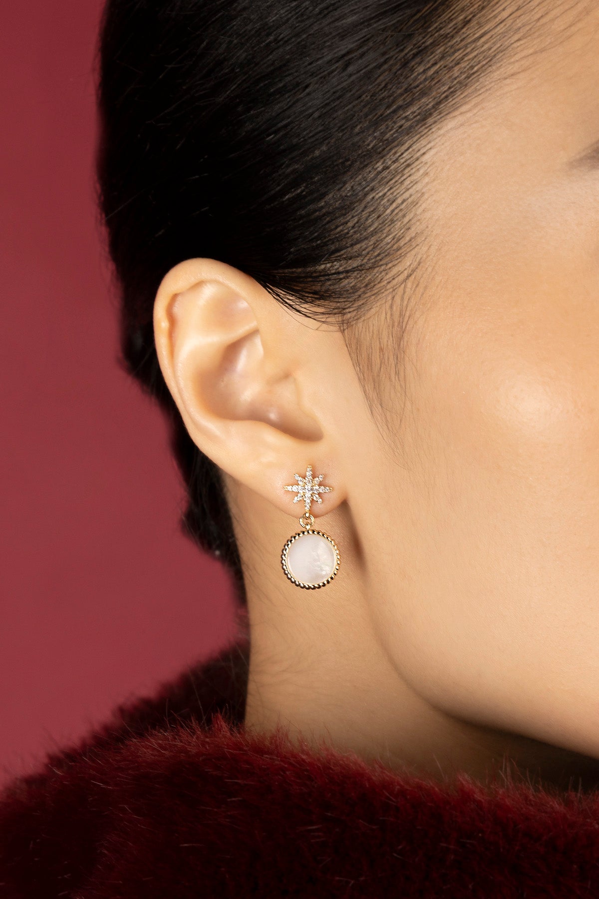 Femme portant les boucles d'oreilles APM, étoile scintillante et médaillon nacré, élégance céleste.