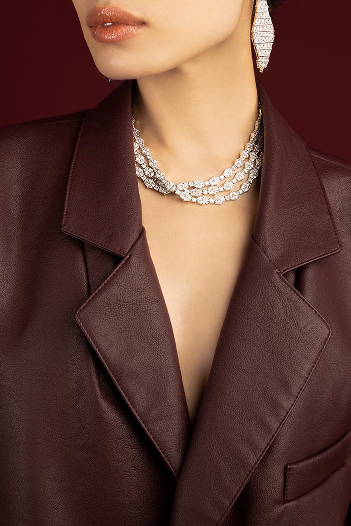 Femme portant un collier APM Monaco multi-rangs, éclat scintillant sur cuir bordeaux.