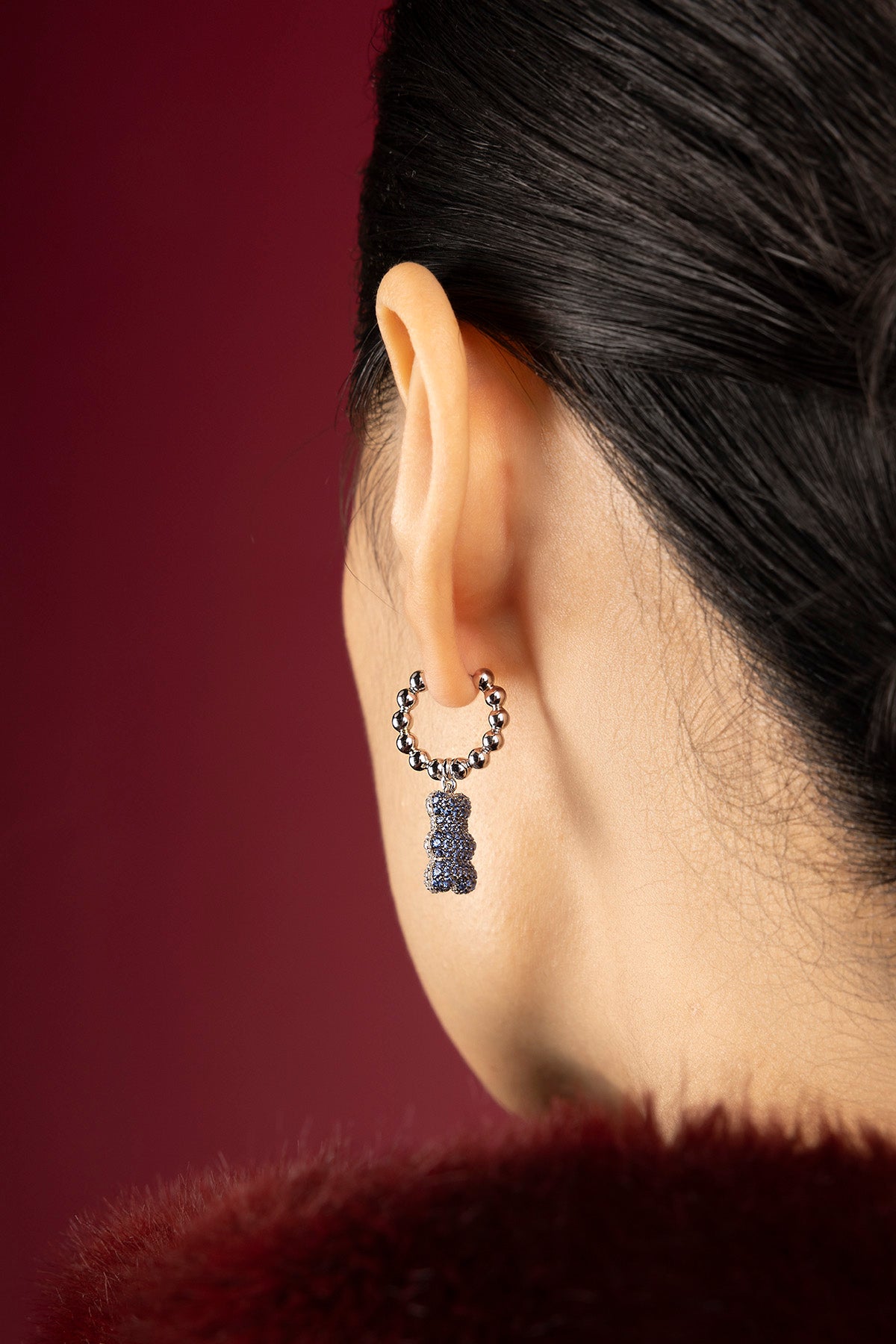 Woman wearing APM Yummy Bear earring, une touche ludique et audacieuse en bleu profond.
