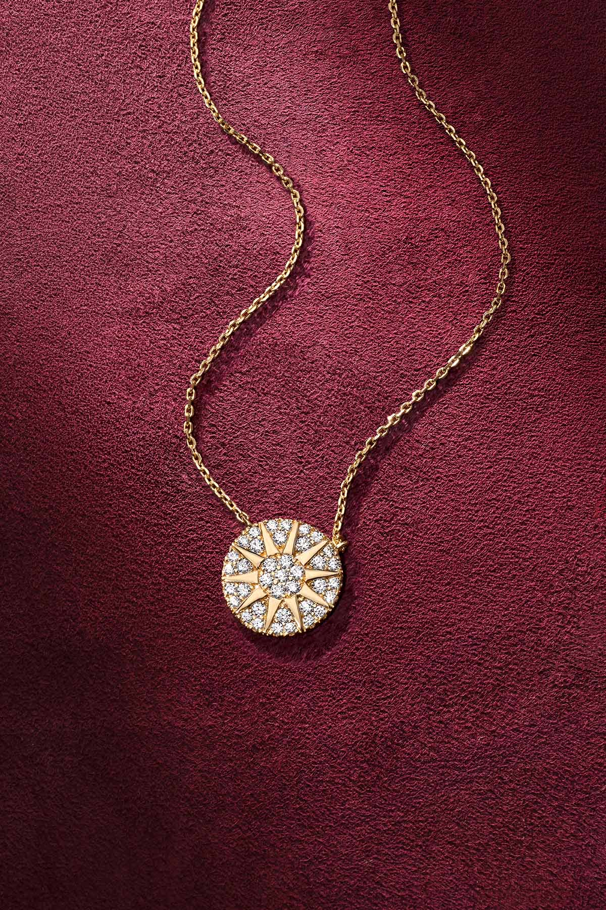 Collier APM aux reflets dorés, un éclat solaire posé sur velours bordeaux.