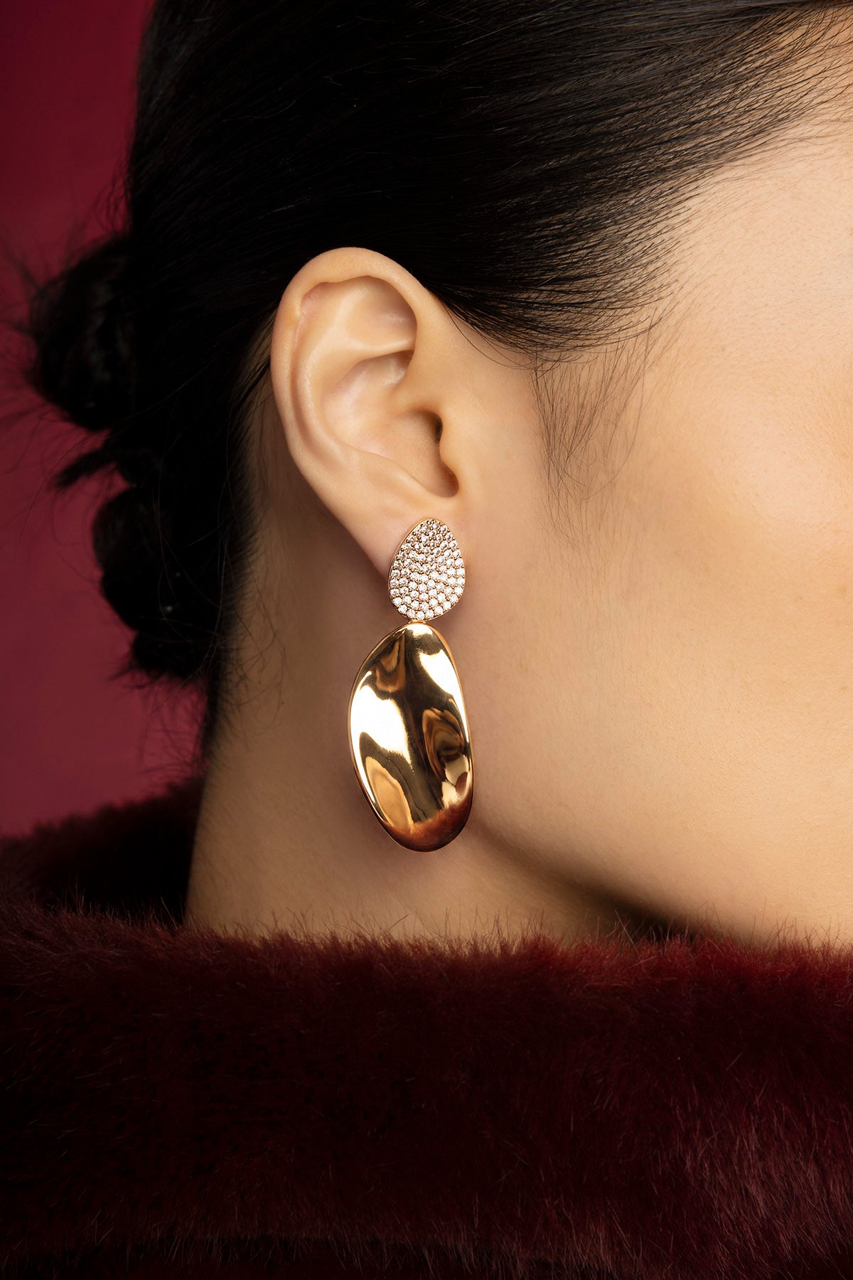 Femme portant les boucles d'oreilles APM Monaco, éclat doré et sophistication moderne.