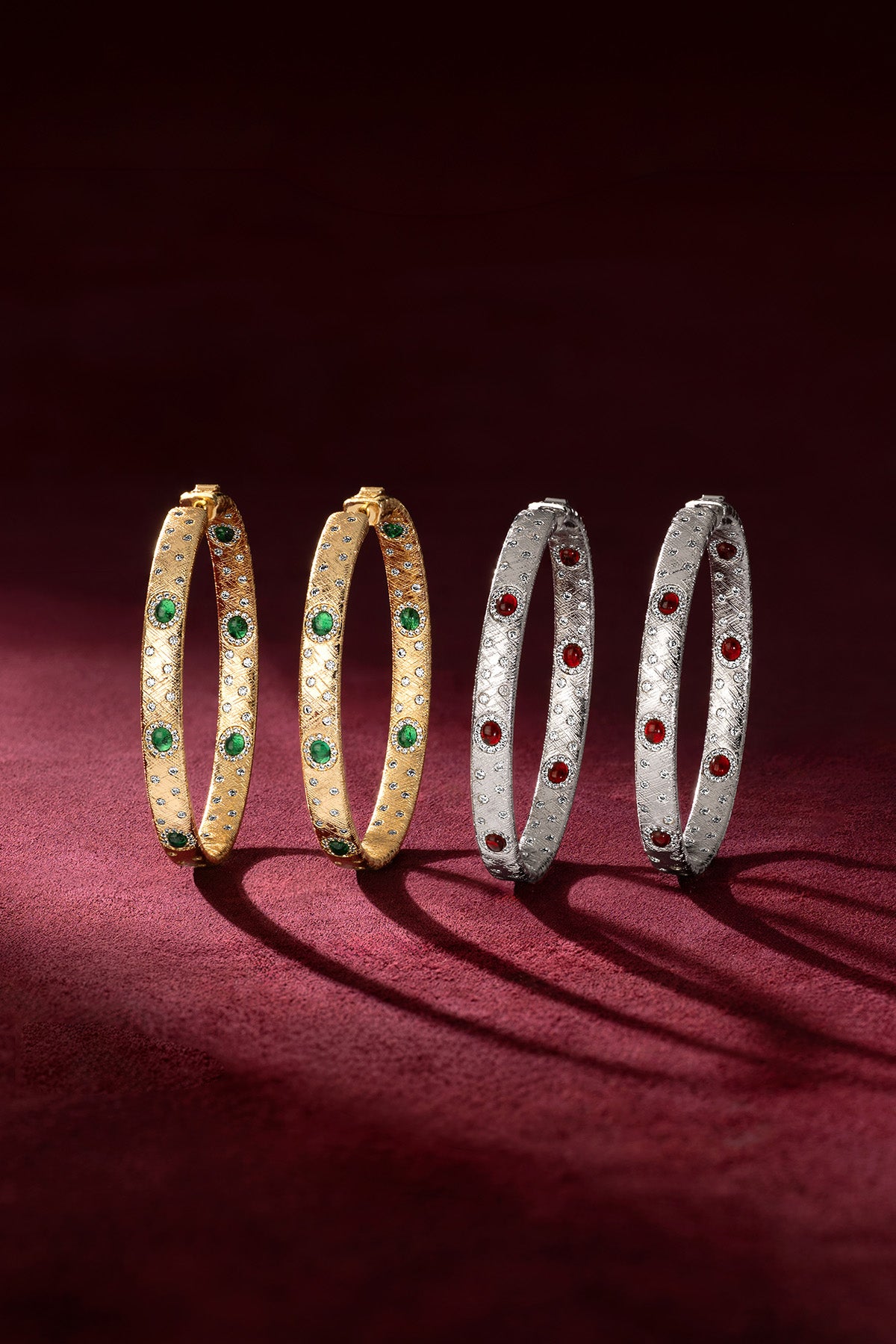 Bracelets APM, duo précieux aux éclats verts et rouges, élégance intemporelle sur velours.