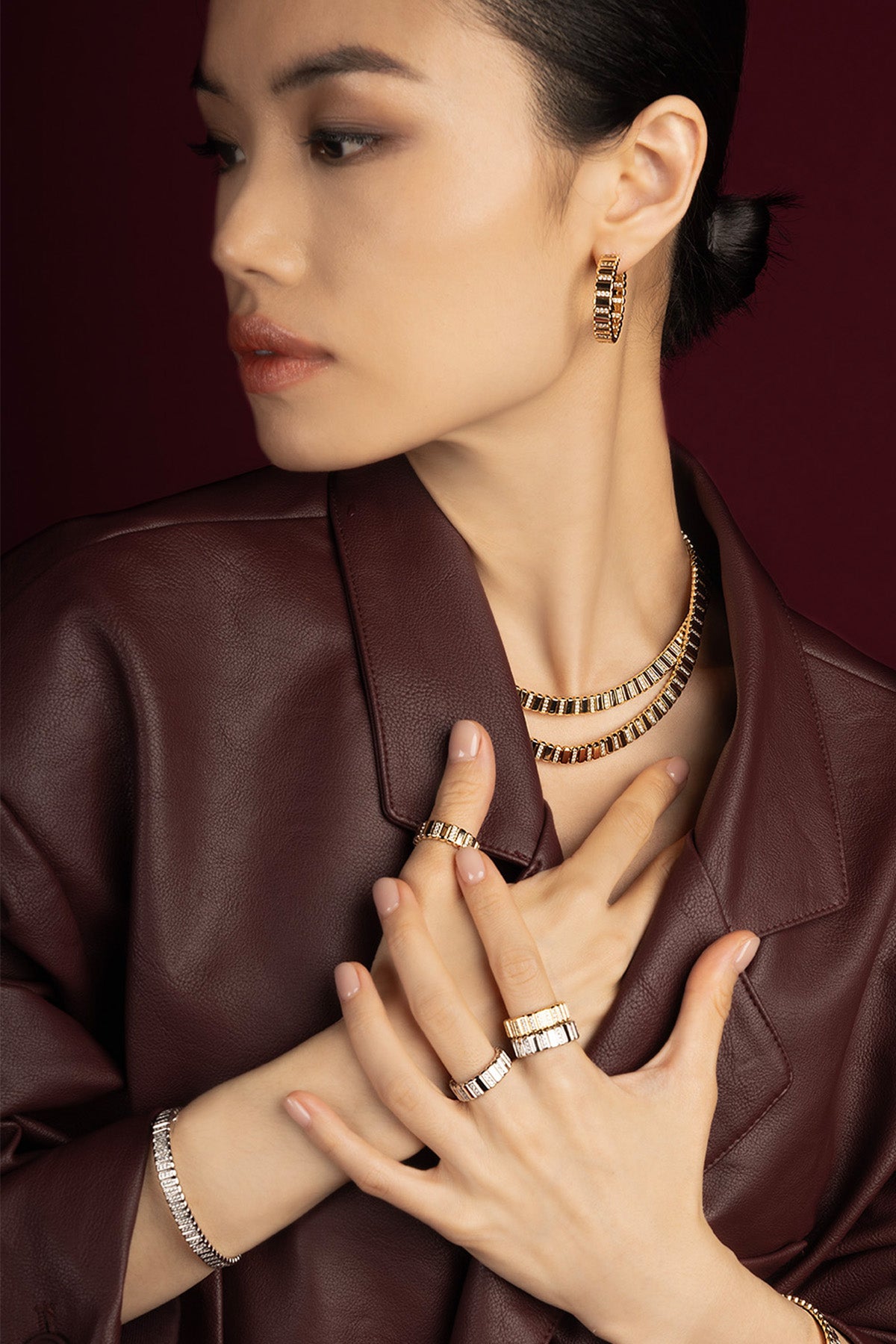 Woman wearing APM Monaco parure dorée, éclat contemporain sur cuir bordeaux.